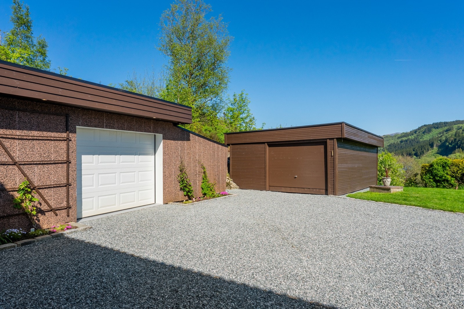 Østside av eiendommen har rikelig med biloppstillingsplasser. Her ser man begge garasjer. Galleribilde