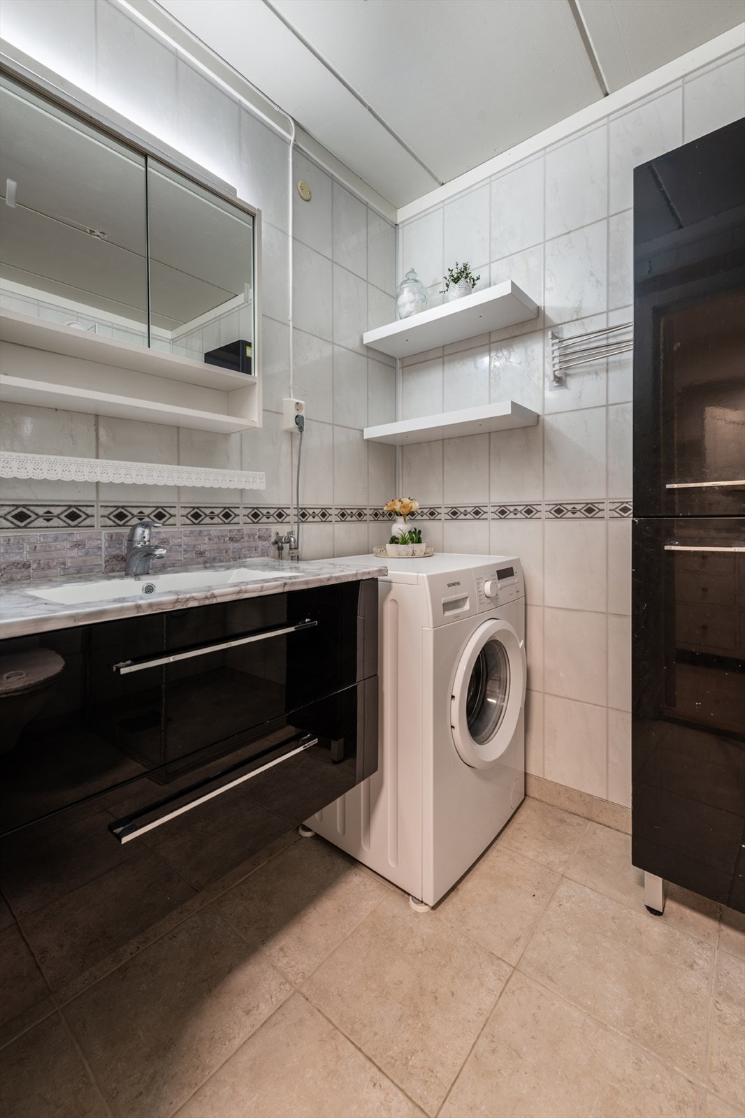 Badet er innredet med servantskap, dusjvegger og vegghengt toalett. Opplegg for vaskemaskin. Galleribilde