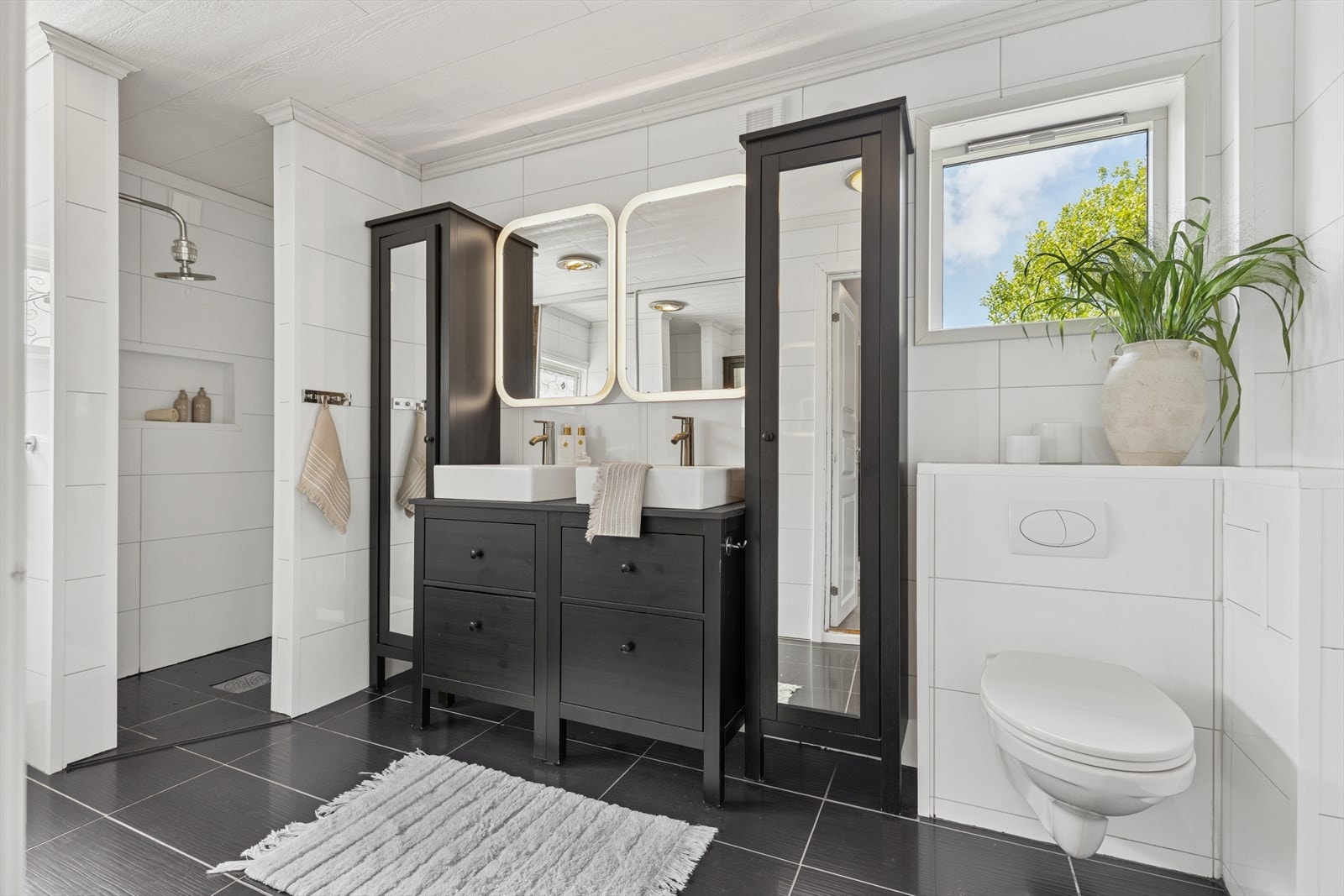 Badet er romslig og oppgradert i moderne stil med mørke møbler, doble servanter, vegghengt toalett og dusjsone med regnfallsdusj. Galleribilde