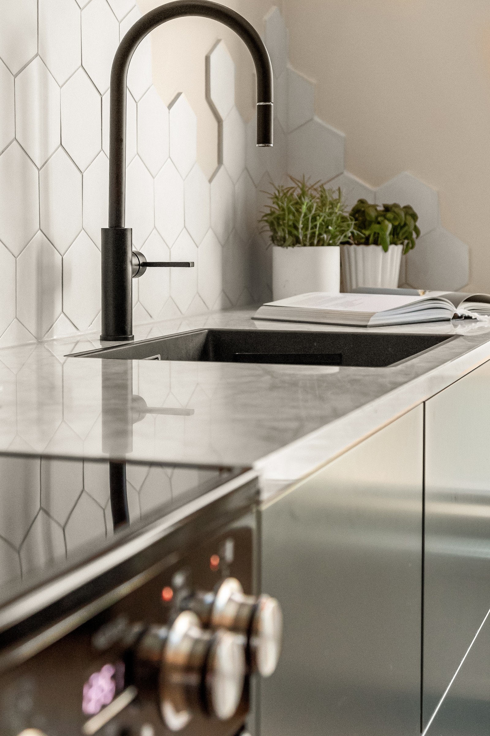 Kjøkkeninnredningen har lekre kombinasjoner med glatte, mørk grå fronter og pen benkeplate av ekte marmorstein med planlimt kum i svartfarget kompositt. Galleribilde