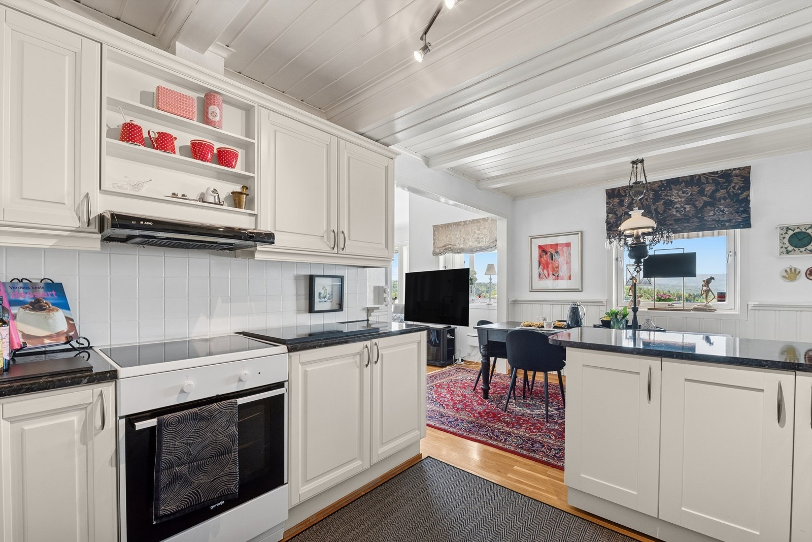 Kjøkkenet har gode og praktiske detaljer som fliser mellom benkeplate og overskap, benkeplate i mørk utførelse og stor kjøkkenservant. Kjøkkenøyen blir en fin forlengelse av innredningen med gode arbeidsflater. Galleribilde