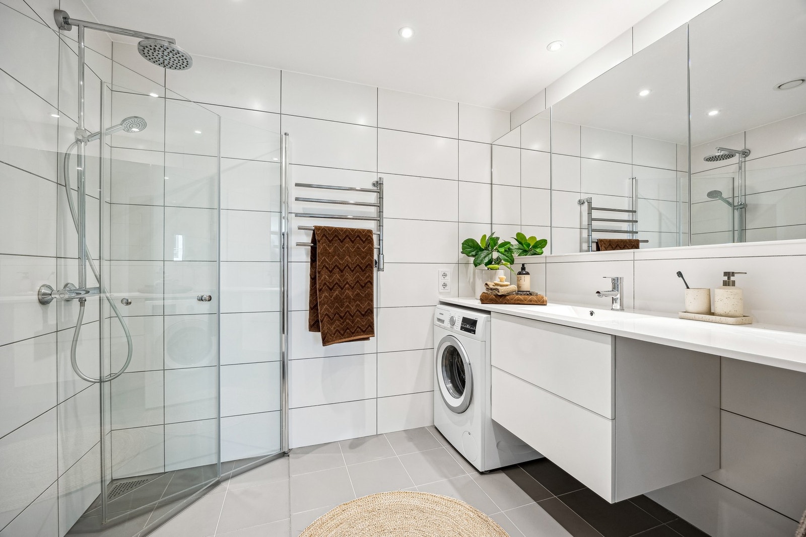 Flott flislagt bad på 5 kvm med gulvvarme. Det er plass til både vaskemaskin og tørketrommel - en på hver side av innredningen. Det er installert regnfallsdusj - for en mer luksuriøs dusjopplevelse. Galleribilde