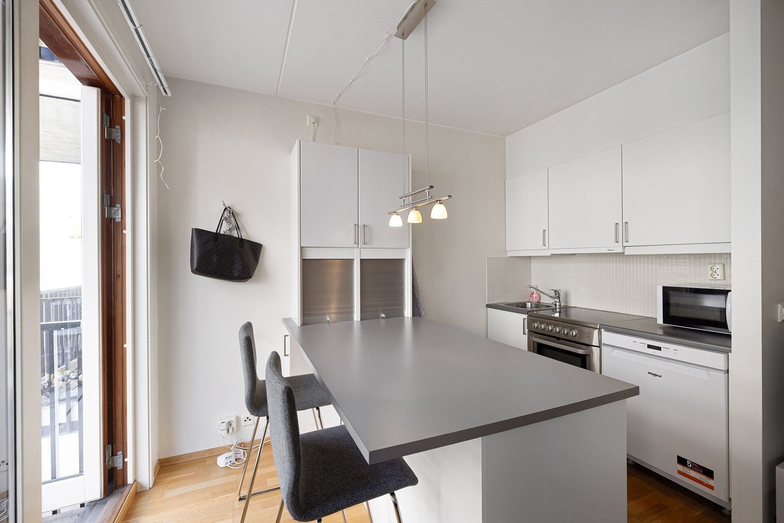 Lys innredning med glatte fronter, flislagt på vegg over kjøkkenbenk og benkeplate i laminat. Galleribilde