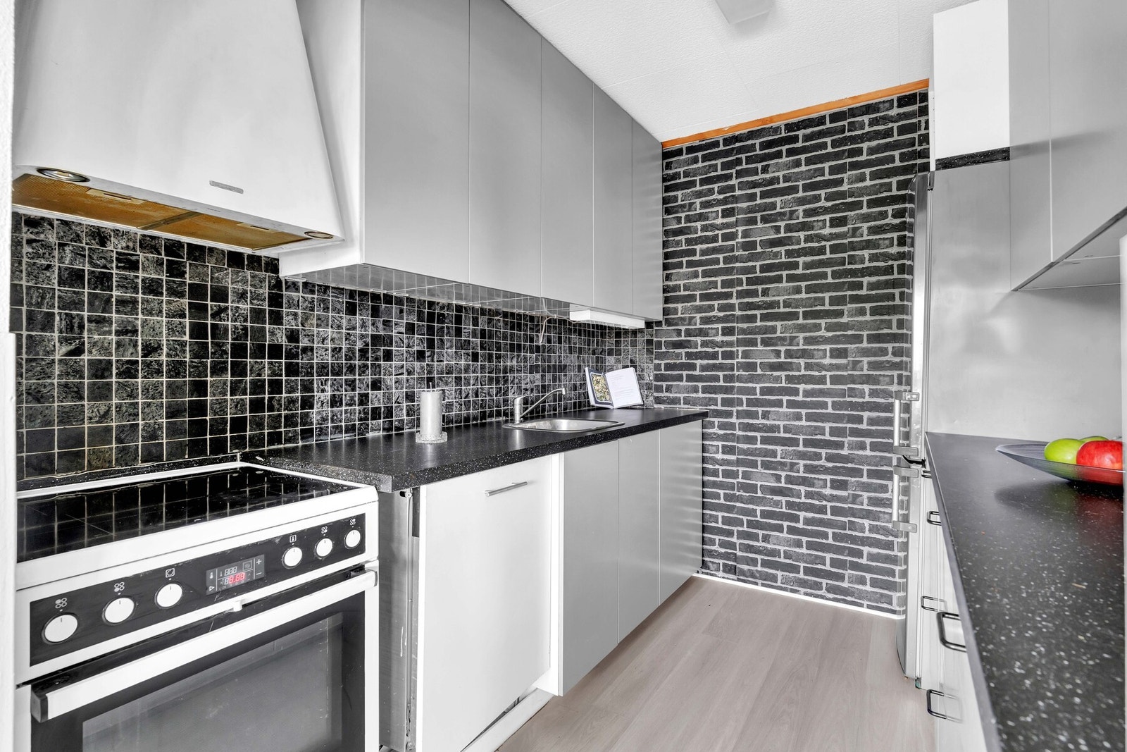 Nisjer til frittstående kjøleskap med frysedel samt komfyr med platetopp. Det er integrert oppvaskmaskin. Galleribilde