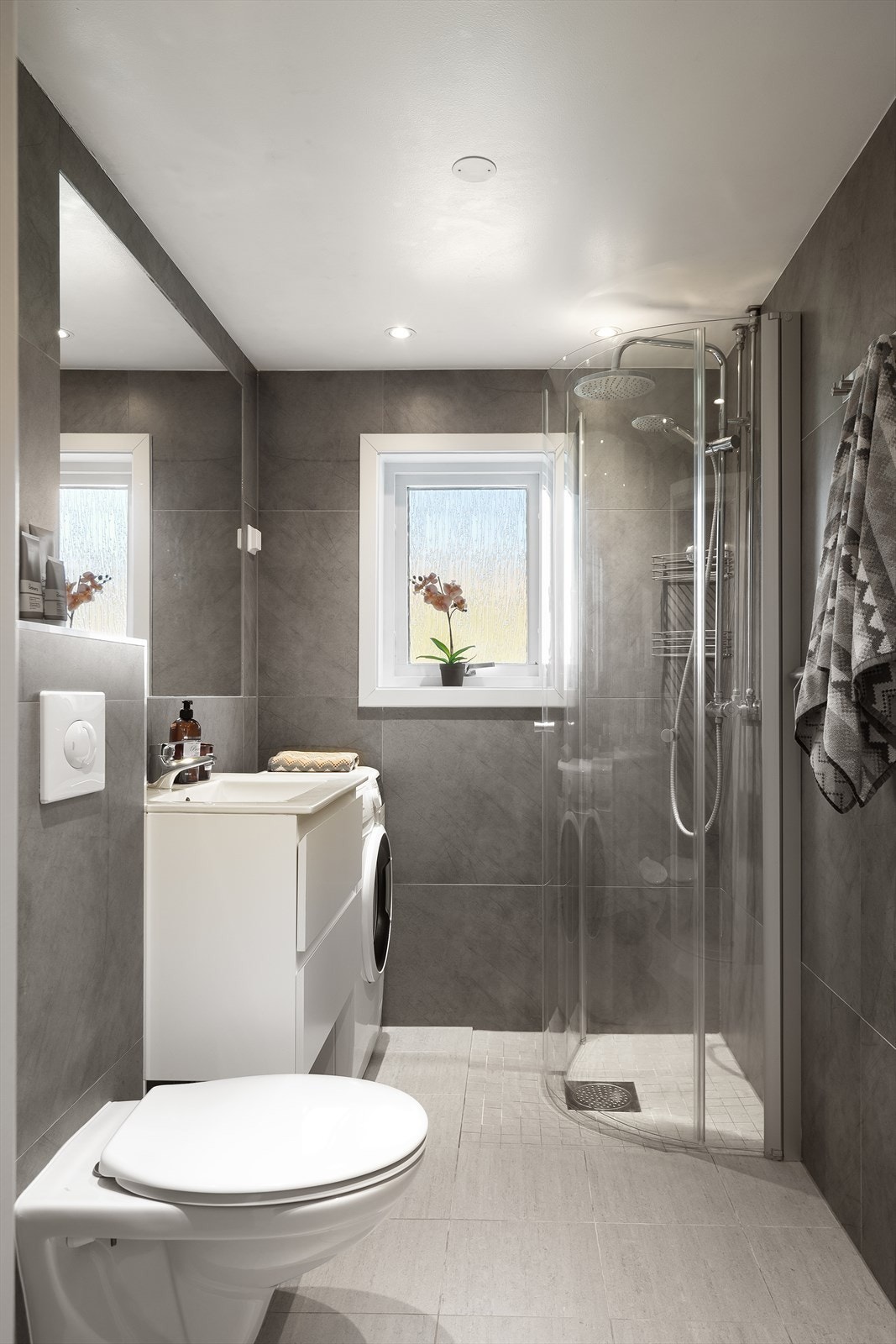 Baderomsinnredningen består av vegghengt klosett, skapinnredning med servant, dusj på gulv med dører i herdet glass. Galleribilde