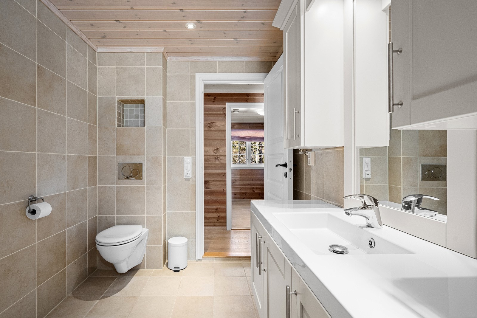 Badet er smakfullt med lyse fliser på gulv og vegger. Galleribilde
