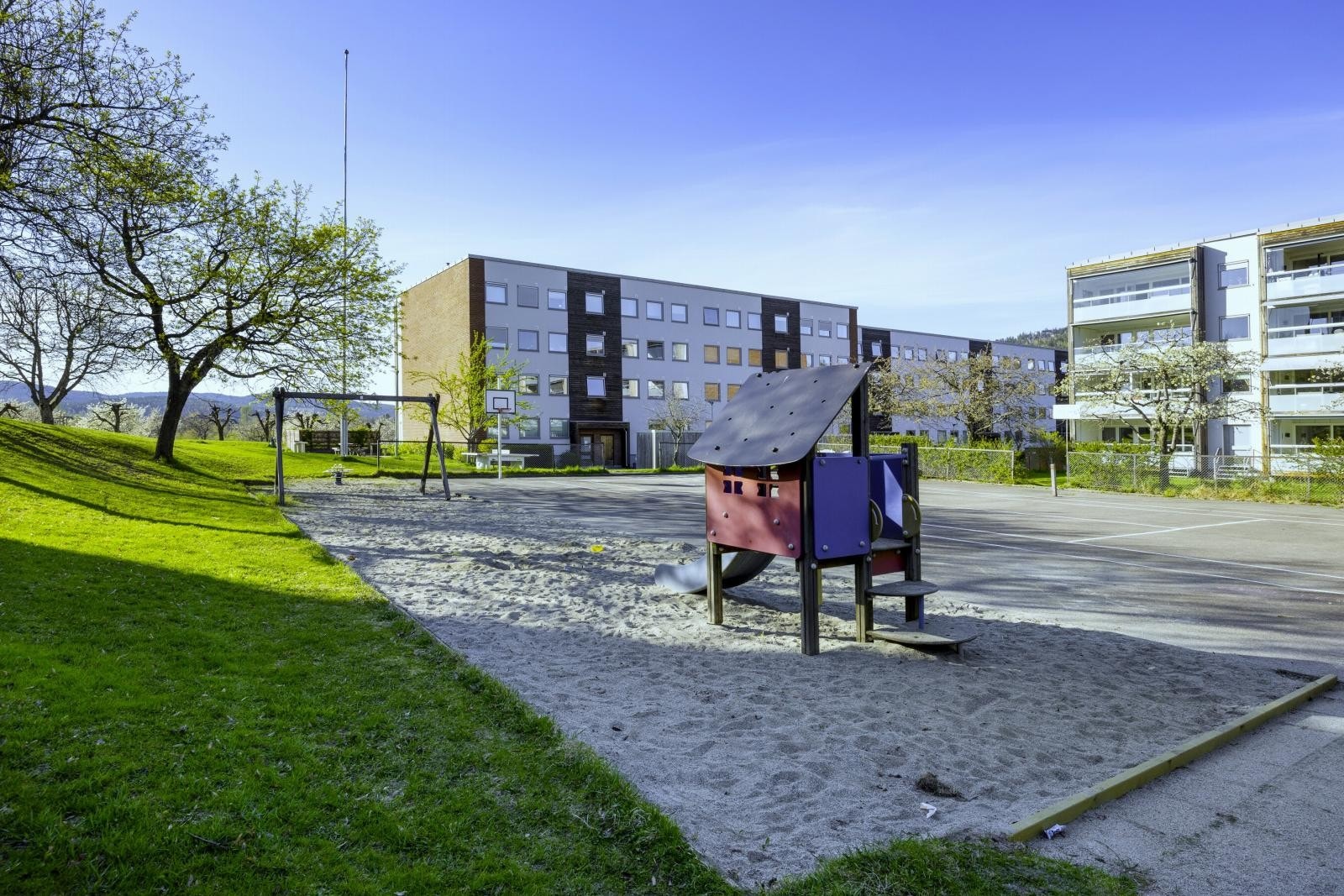 Tomten er pent opparbeidet med asfalterte internveier, belegningsstein, gressplener og variert beplantning, lekeapparater og sittegrupper. Galleribilde