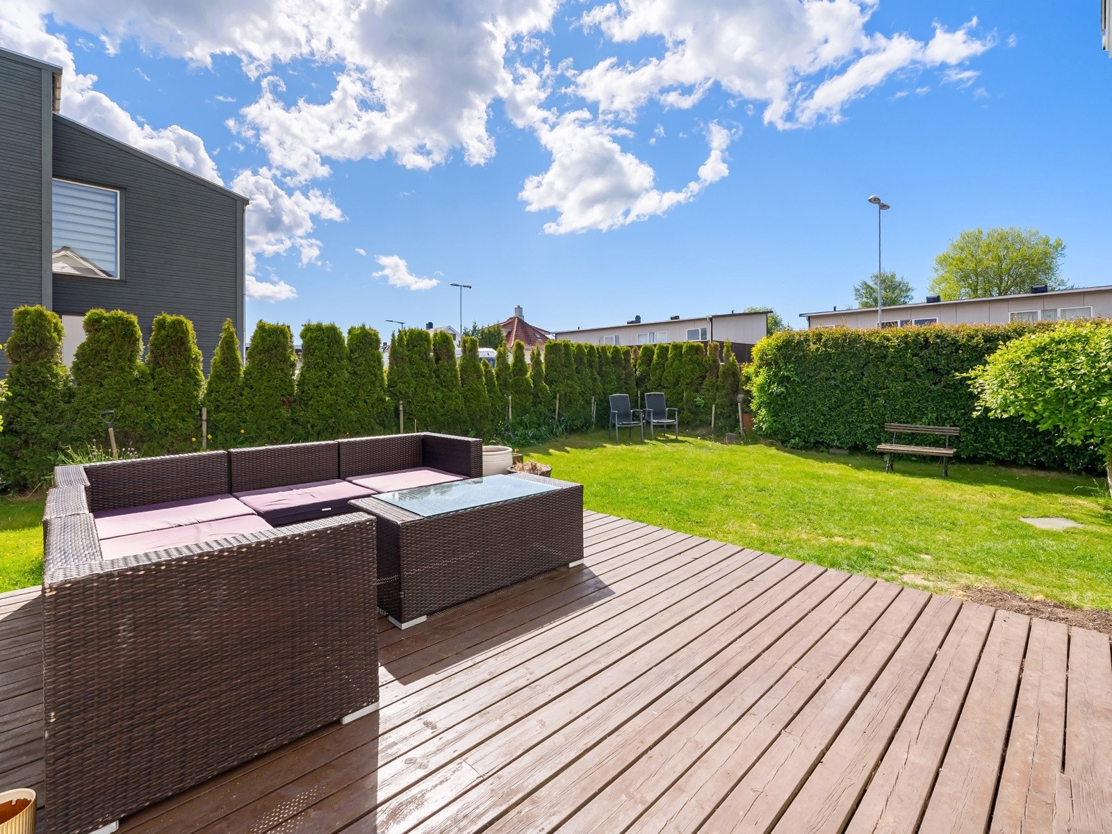 Fra stuen er det utgang til et pent uteområde med terrasseplatting og hage med plen Galleribilde