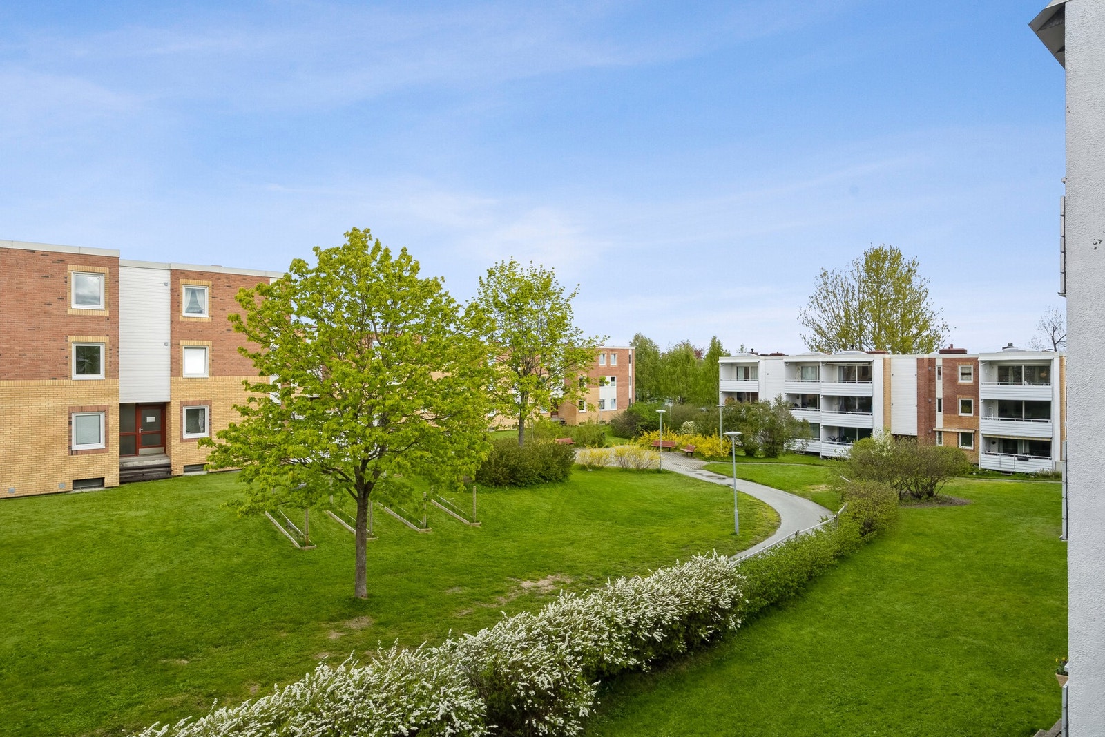 Fra balkongen har man utsikt innover borettslaget, godt med plass mellom blokkene og lite innsyn. Galleribilde
