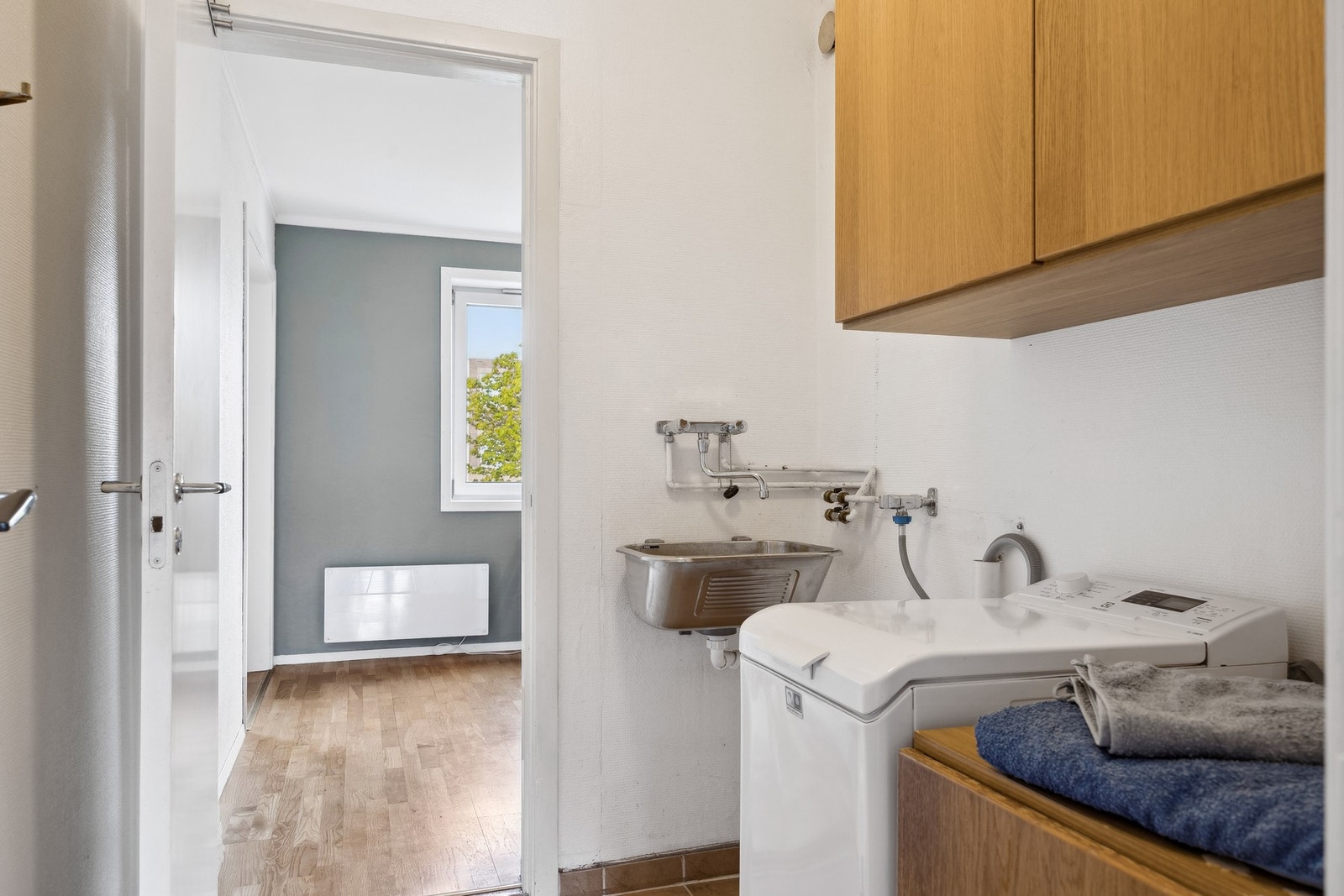 Vaskerommet er innredet med skap, vask og opplegg for vaskemaskin. Galleribilde