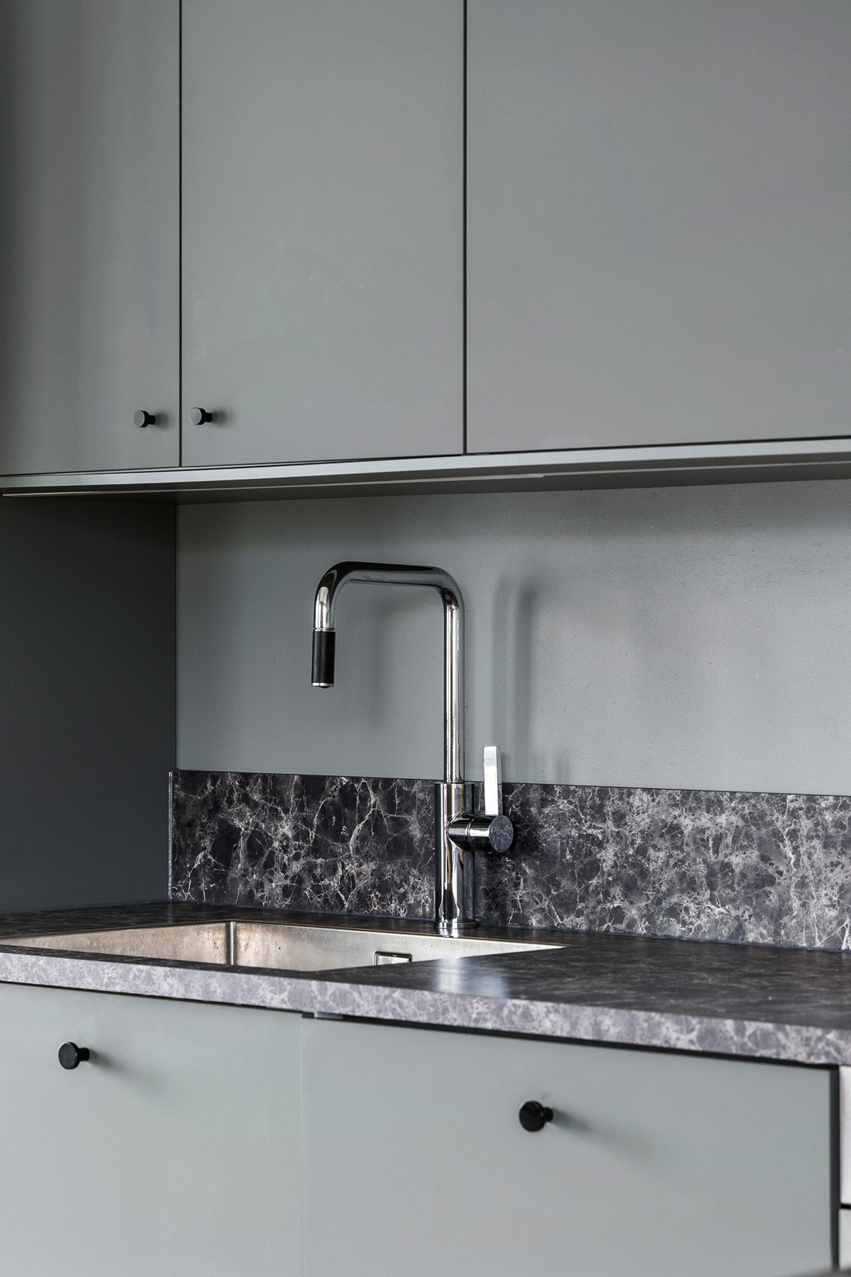 Kjøkkeninnredning med slette fronter, laminat benkeplate og fliser over benk Galleribilde