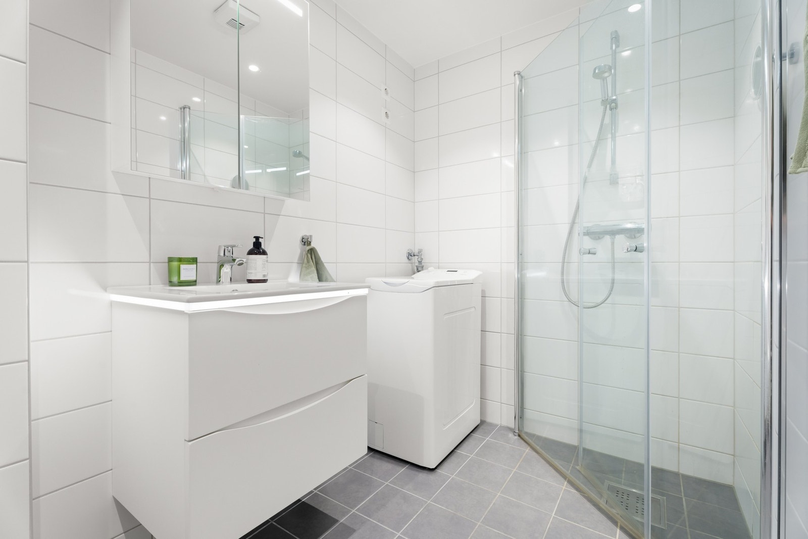 Innredning med skuffeseksjon med servant, overskap dusj på vegg med glassdører Galleribilde