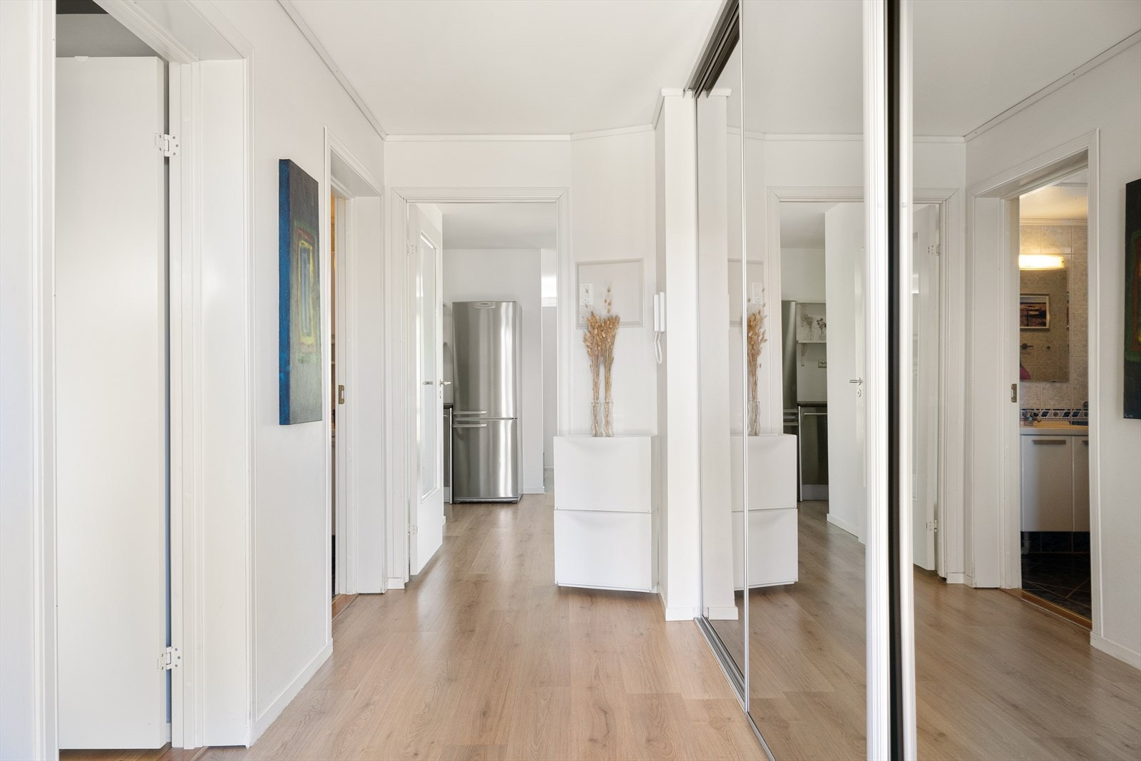 Her er det en stor skyvedørsgarderobe med speil som både åpner rommet og skjuler klær og sko på en ryddig måte. Galleribilde