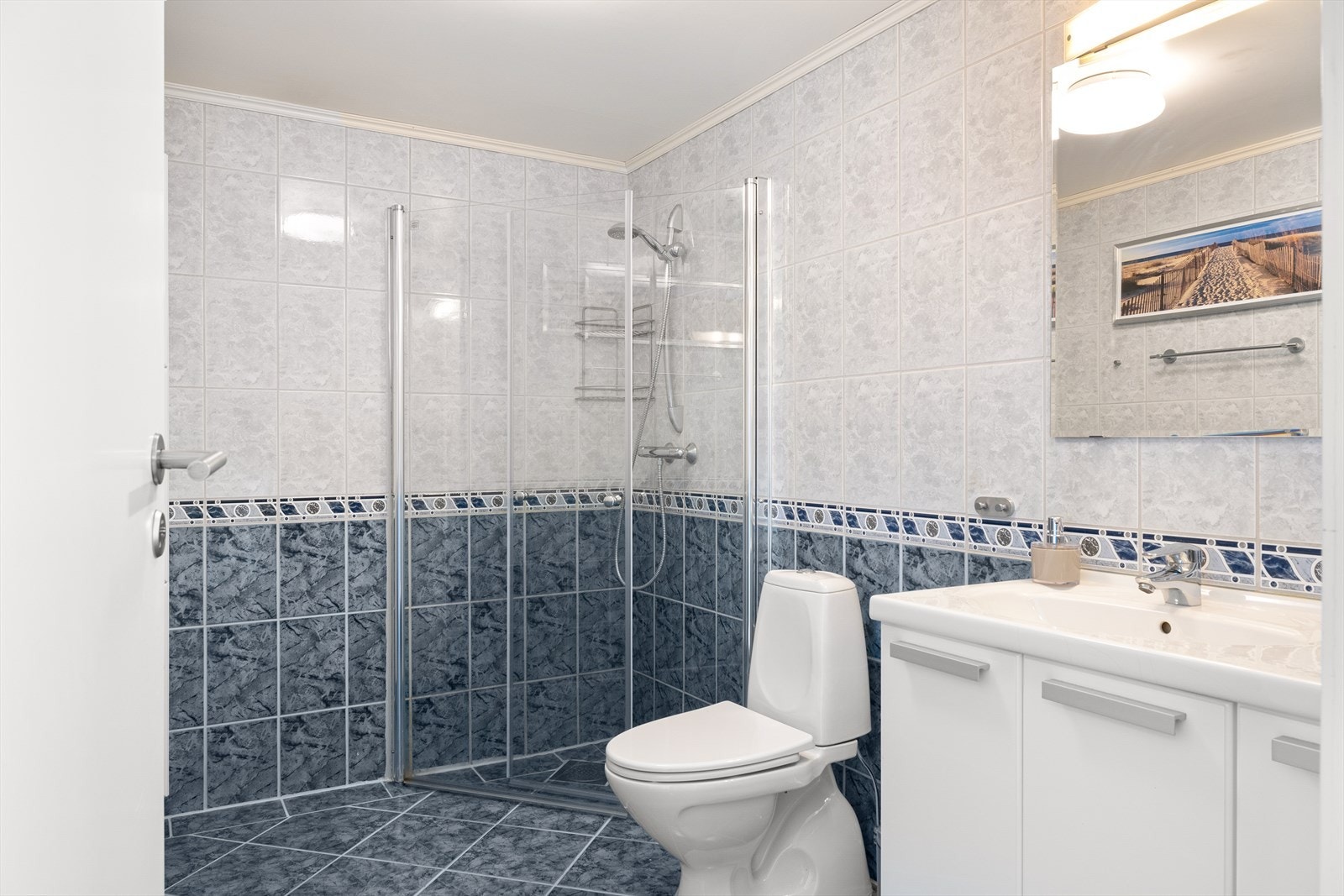 Rommet er innredet med vegghengt servant, toalett og dusjløsning. Galleribilde