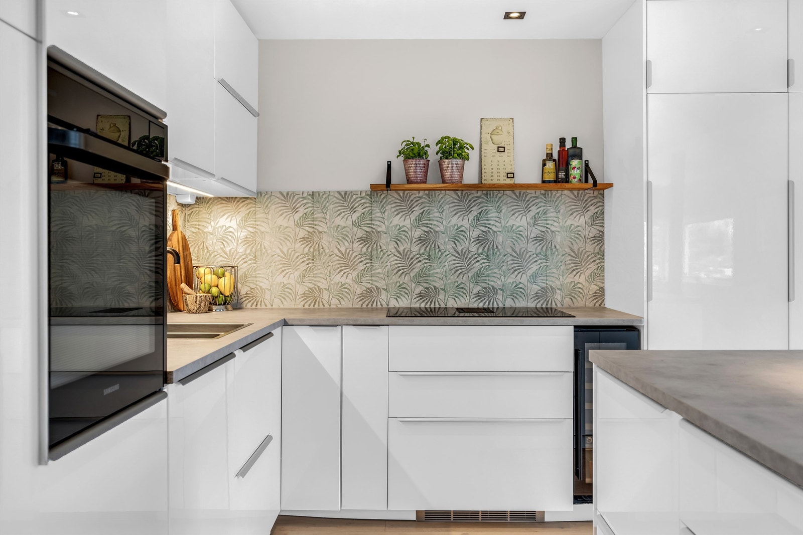 Kjøkken med integrerte hvitevarer som stekeovn, induksjonstopp, vinskap, kjøl-fryseskap og oppvaskmaskin Galleribilde