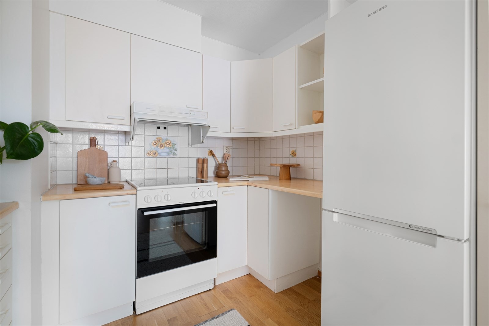 Kjøkkeninnredning med glatte fronter. Frittstående kjøleskap med fryser, komfyr med platetopp og oppvaskmaskin. Galleribilde