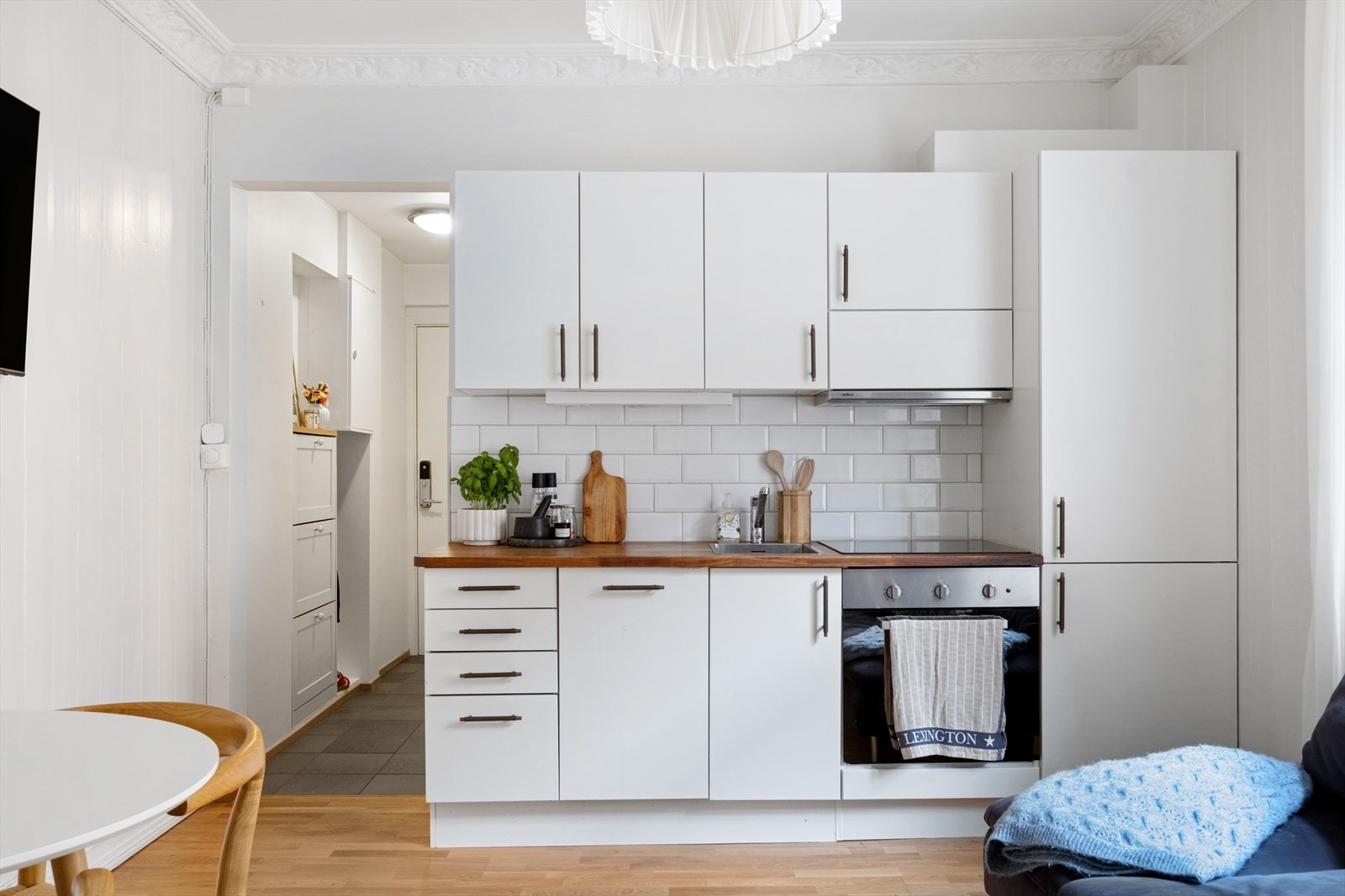 Kjøkkeninnredning med glatte fronter, heltre benkeplate med nedfelt vask og integrert platetopp, stekeovn, oppvaskmaskin og kjøl/fryseskap. Galleribilde