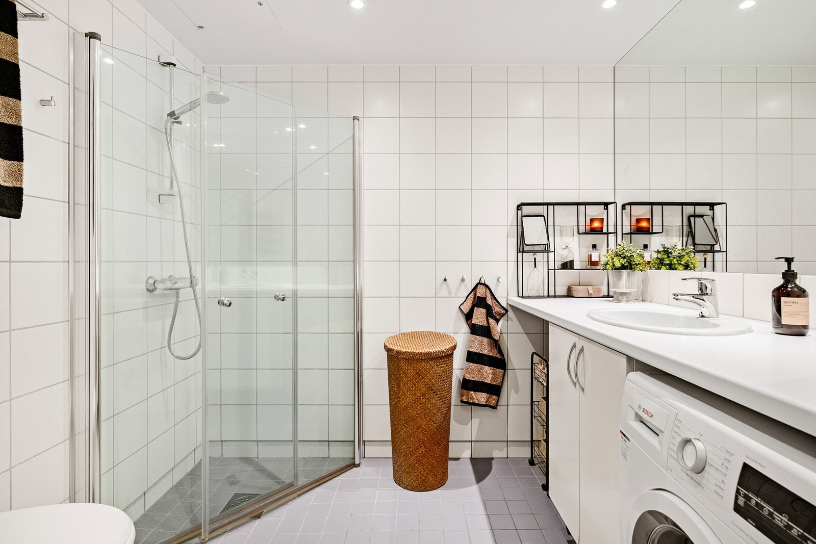 Lyst, flislagt bad med varme i gulv og downlights i himling. Badet har opplegg for vaskemaskin og plass til tørketrommel plassert under benk. Galleribilde