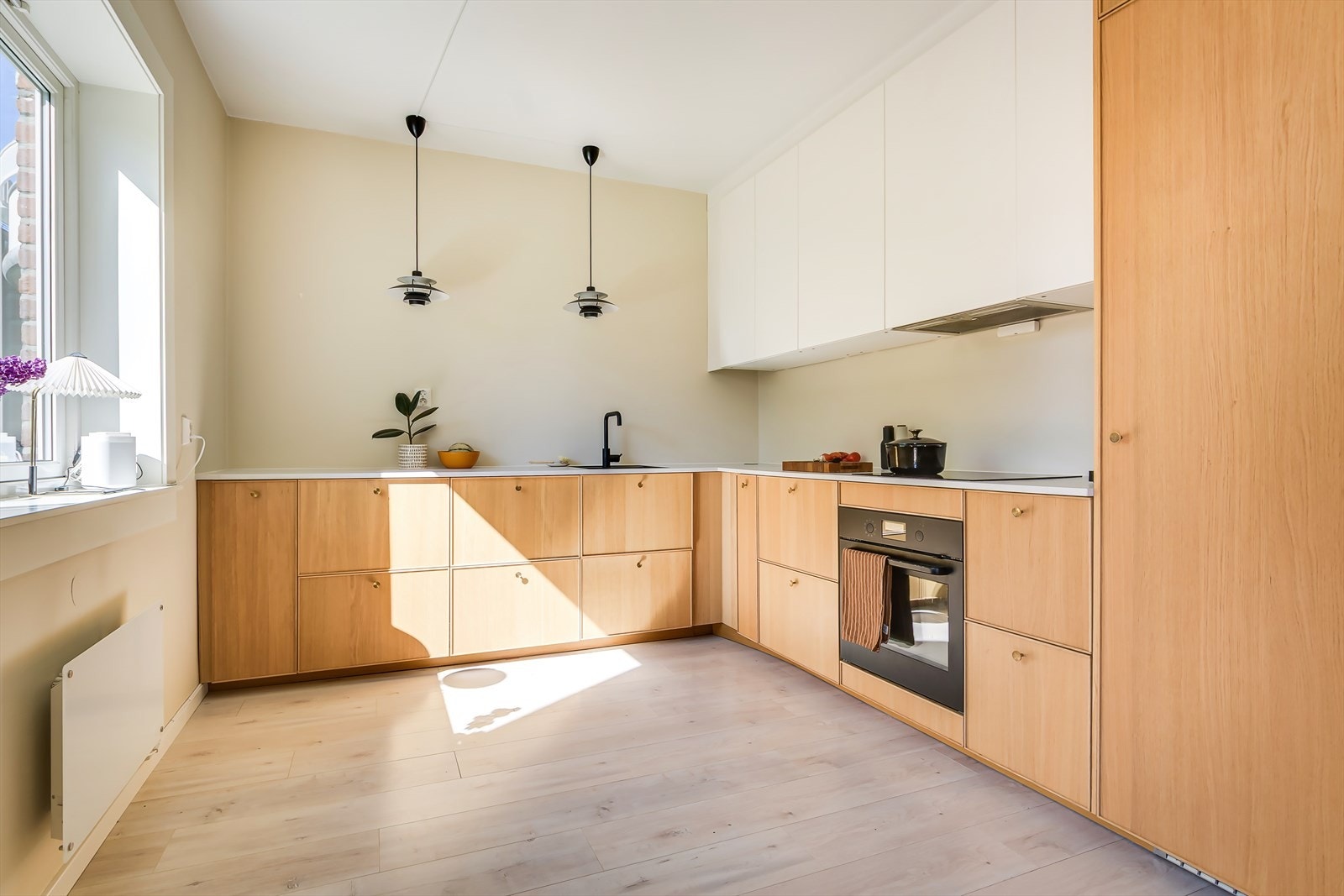 Pent og romslig kjøkken fra 2020 med slette fronter i lys eik og benkeplate i laminat Galleribilde