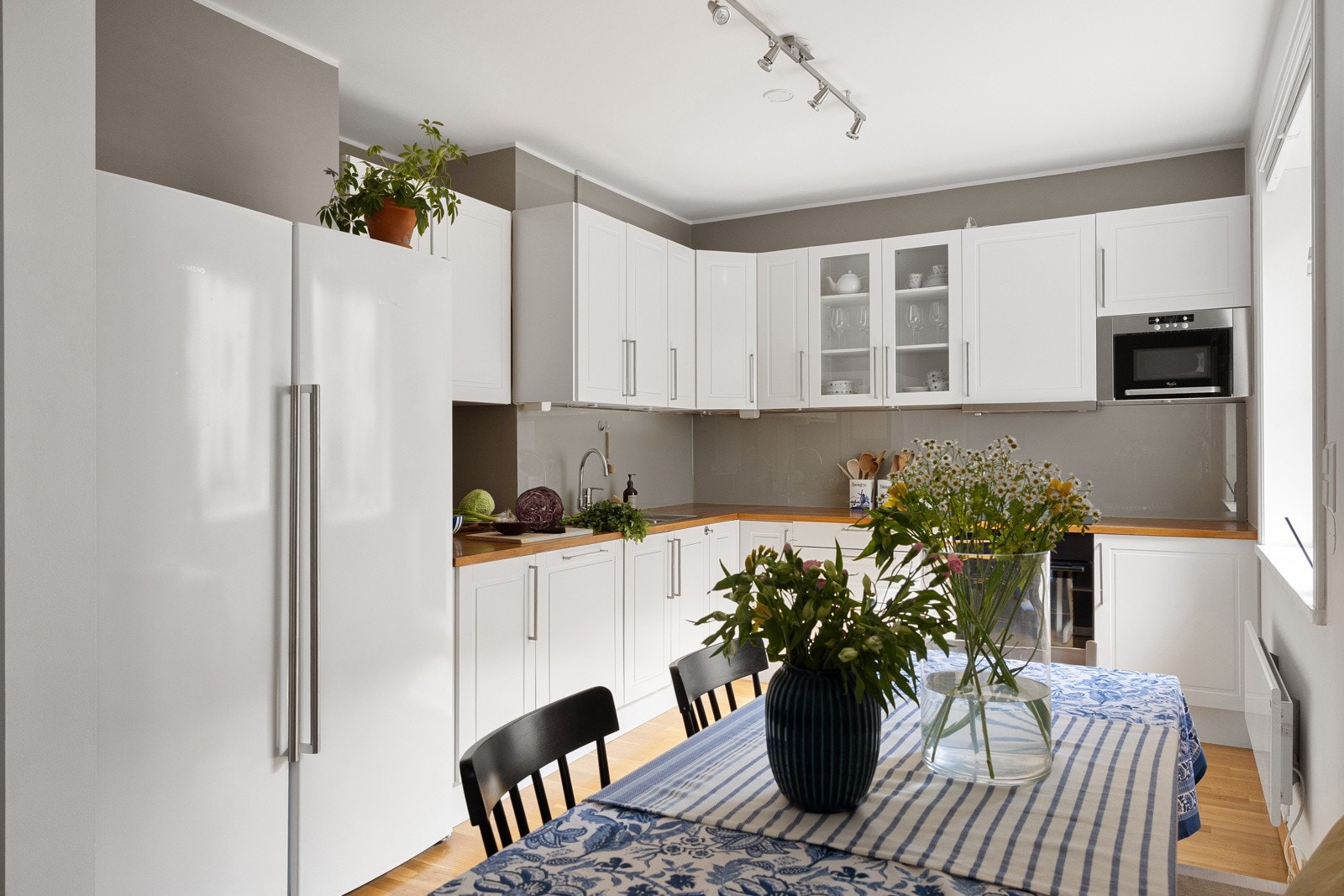 På kjøkkenet er det også hyggelig spiseplass, og åpningen mellom kjøkkenet og stuen gjør det enkelt å dekke opp til langbord for mange kuverter Galleribilde