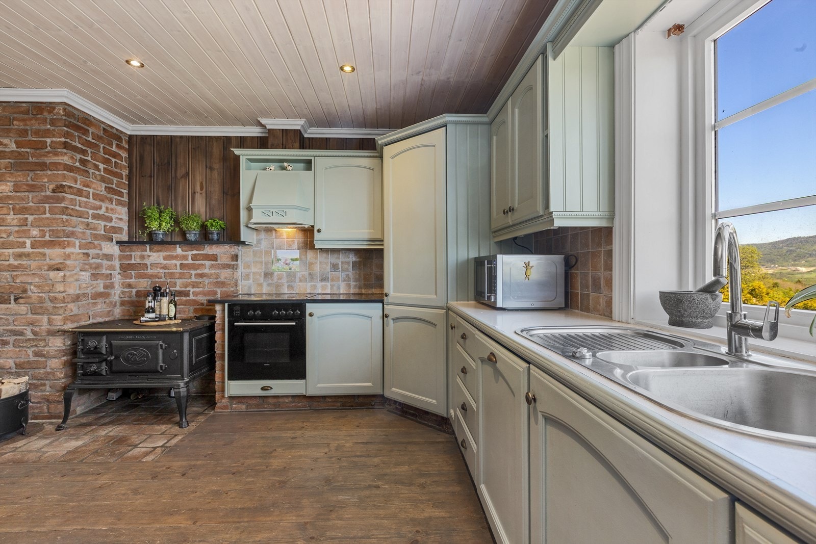 Støpejernsovnen og teglpipen er kulisser som gir kjøkkenet en varm og god atmosfære Galleribilde