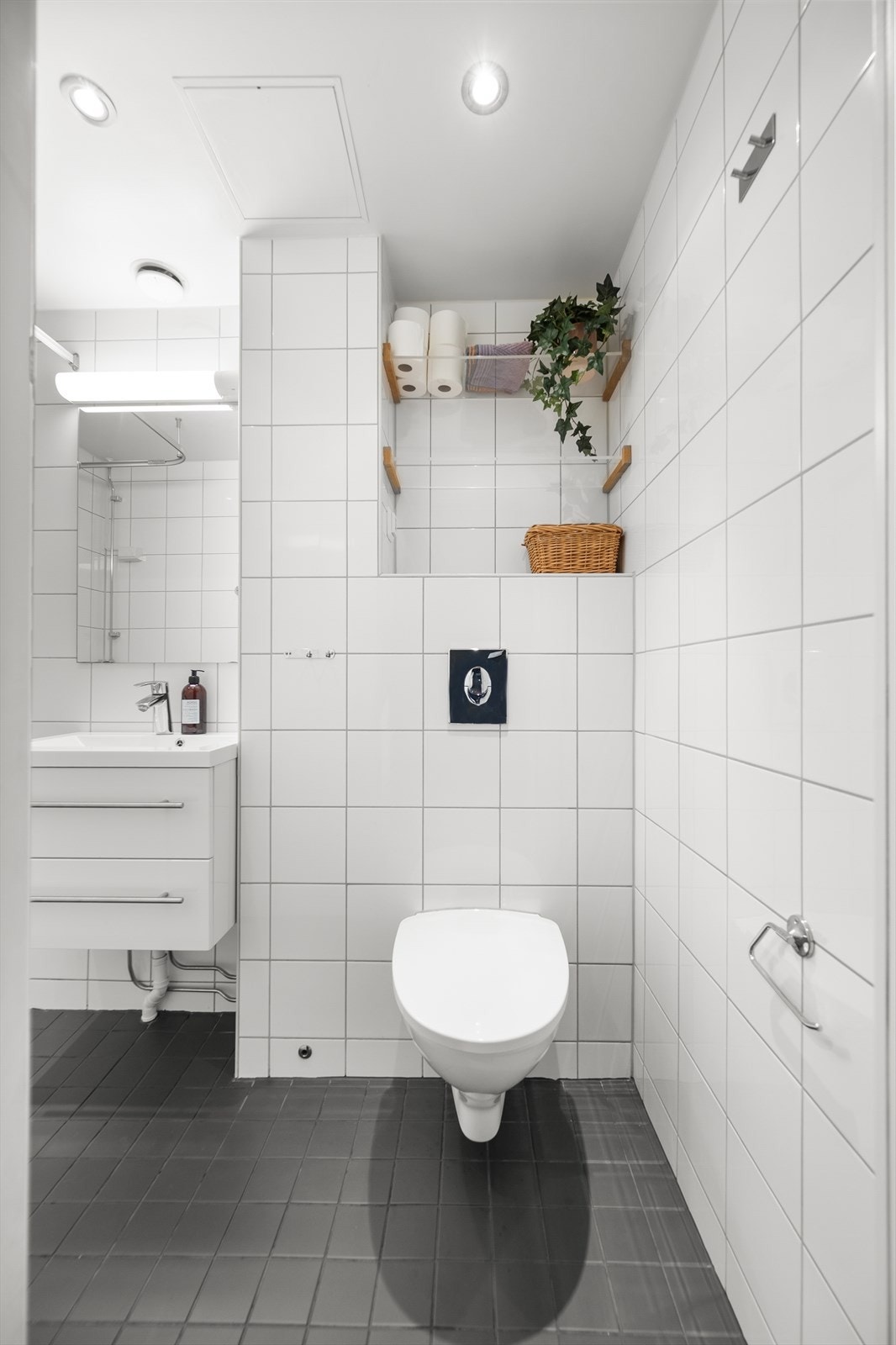 Badet er innredet med vegghengt toalett, dusjhjørne med forheng og baderomsinnredning med skuffer, servant nedfelt i innredning og vegghengt speilskap. Galleribilde