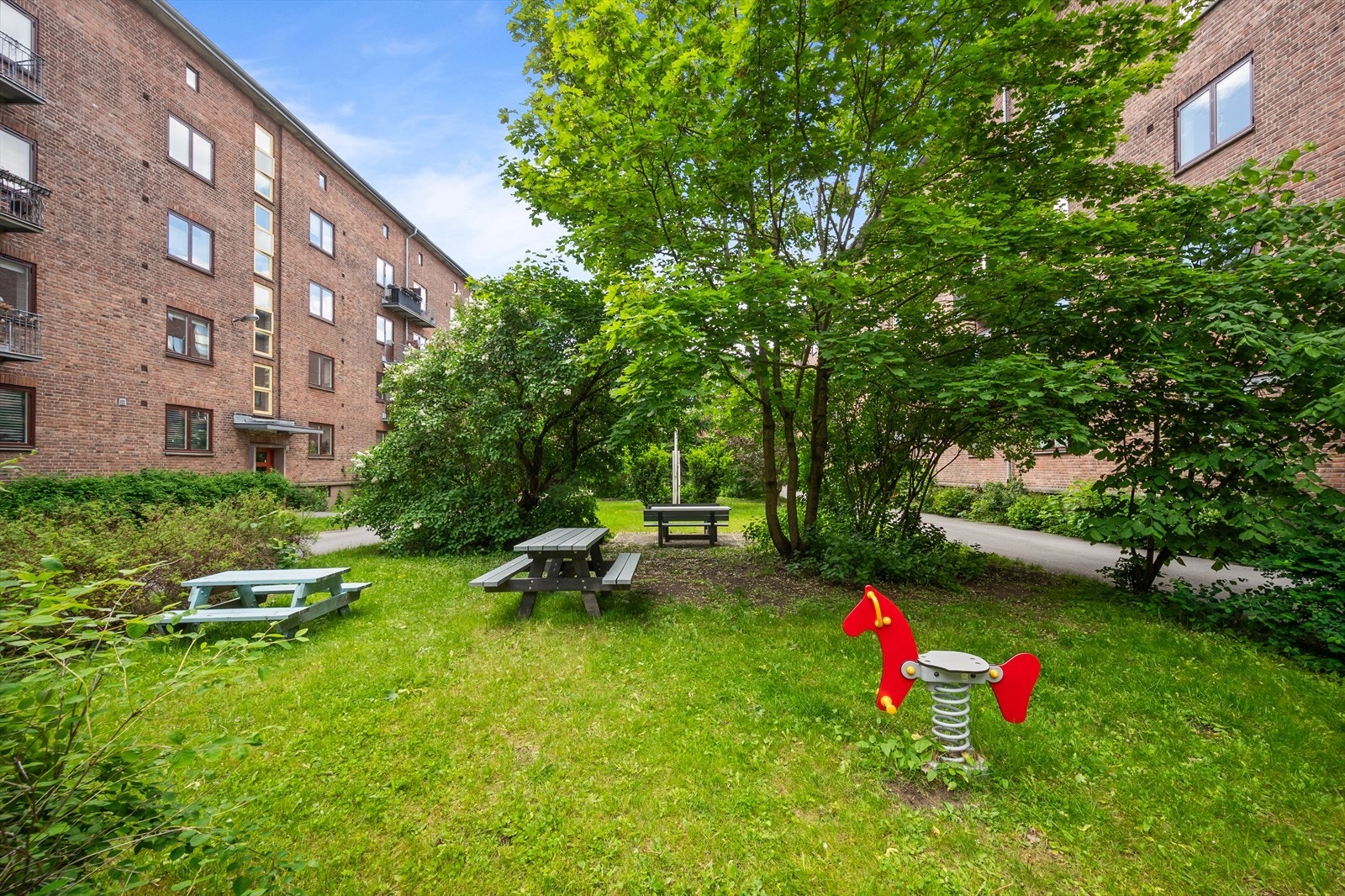 Den idylliske bakgården er pent opparbeidet med plen og beplanting. Det er flere sittegrupper og sykkelparkering for beboerne. Galleribilde