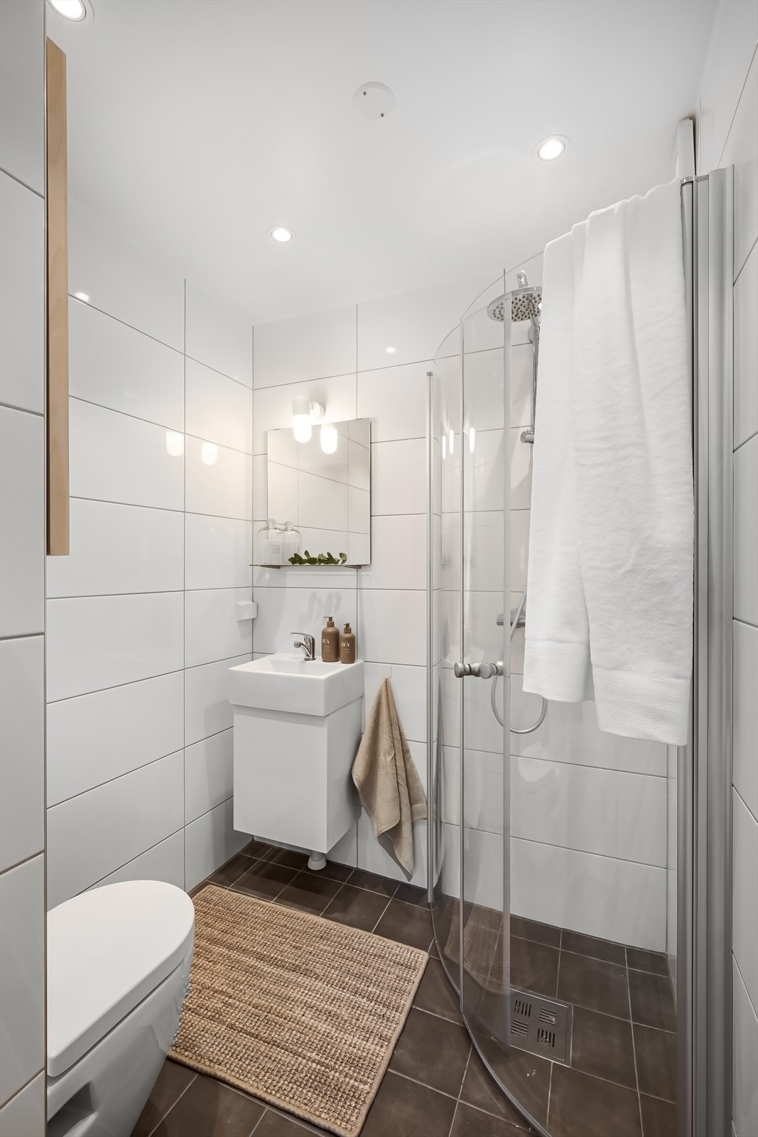 Badet er flislagt med varmekabler og innredning med vegghengt toalett, dusjhjørnet, servant og speil. Galleribilde