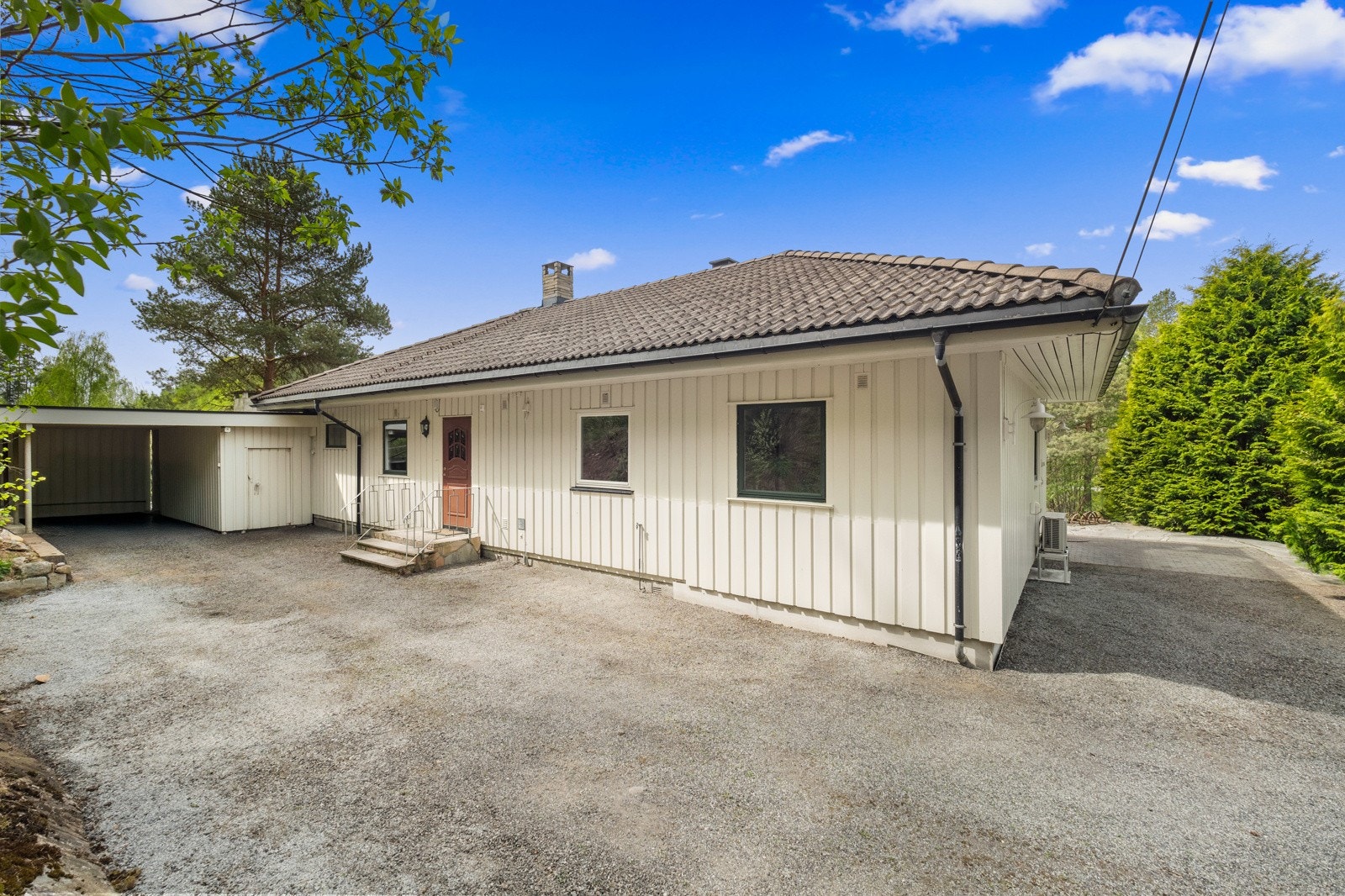 Gårdsplassen på baksiden har en carport i enden, i bakkant av en overbygget terrasse. Galleribilde