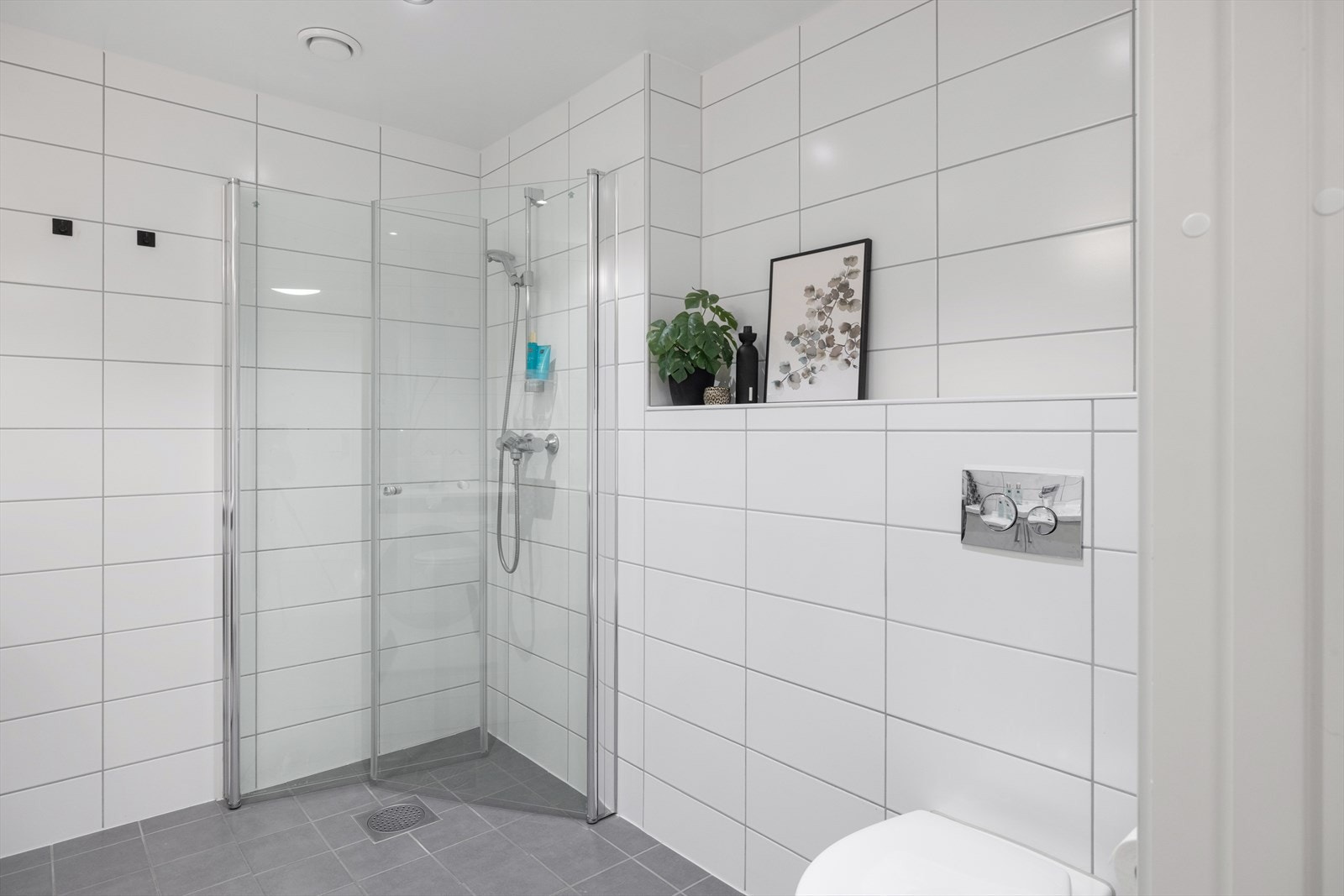 Baderomsinnredningen består av servant med skapinnredning, speil, belysning, veggmonterte dusjvegger i dusjhjørne, veggmontert klosett og opplegg for vaskemaskin. Galleribilde