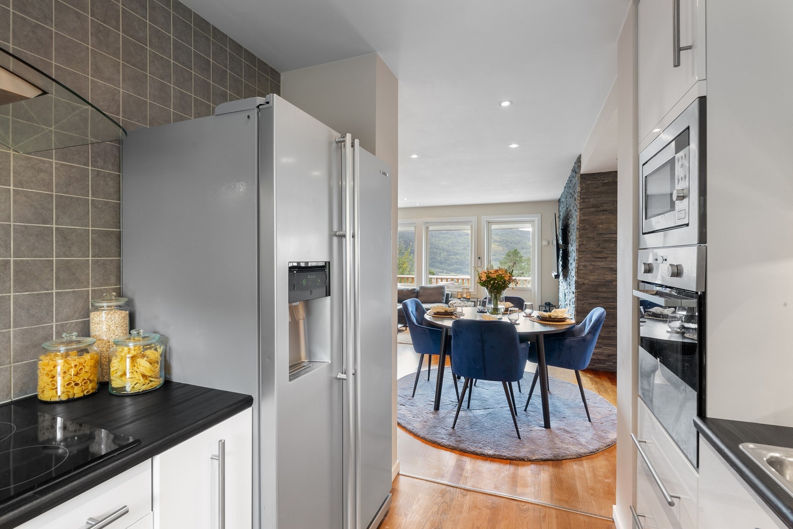 Flislagte felt/vegger over benkeplater av laminat og lysarmaturer under overskap Galleribilde