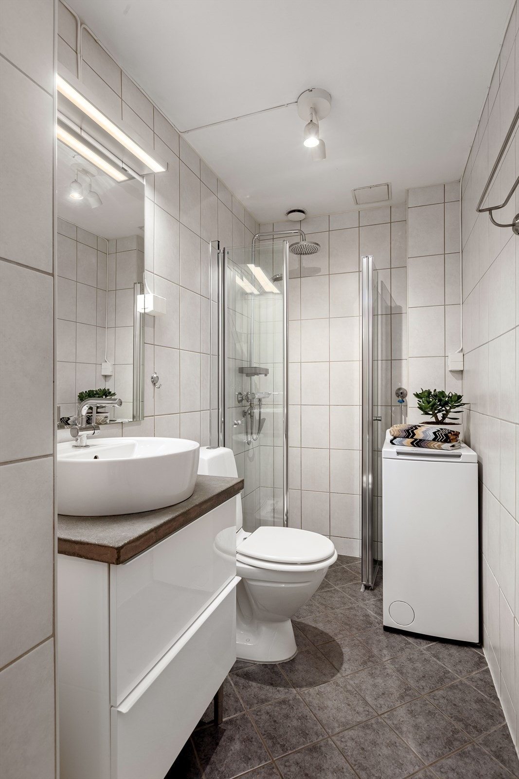 Delikat bad med dusjhjørne, wc, servant med skuffer og opplegg for vaskemaskin. Galleribilde