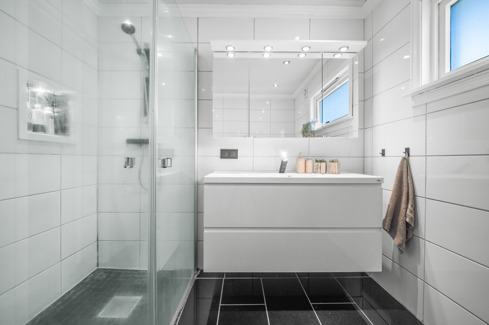 Badet er innredet med servantinnredning med ovenpåliggende servant, dusjhjørne med innfellbare dører, samt vegghengt toalett Galleribilde