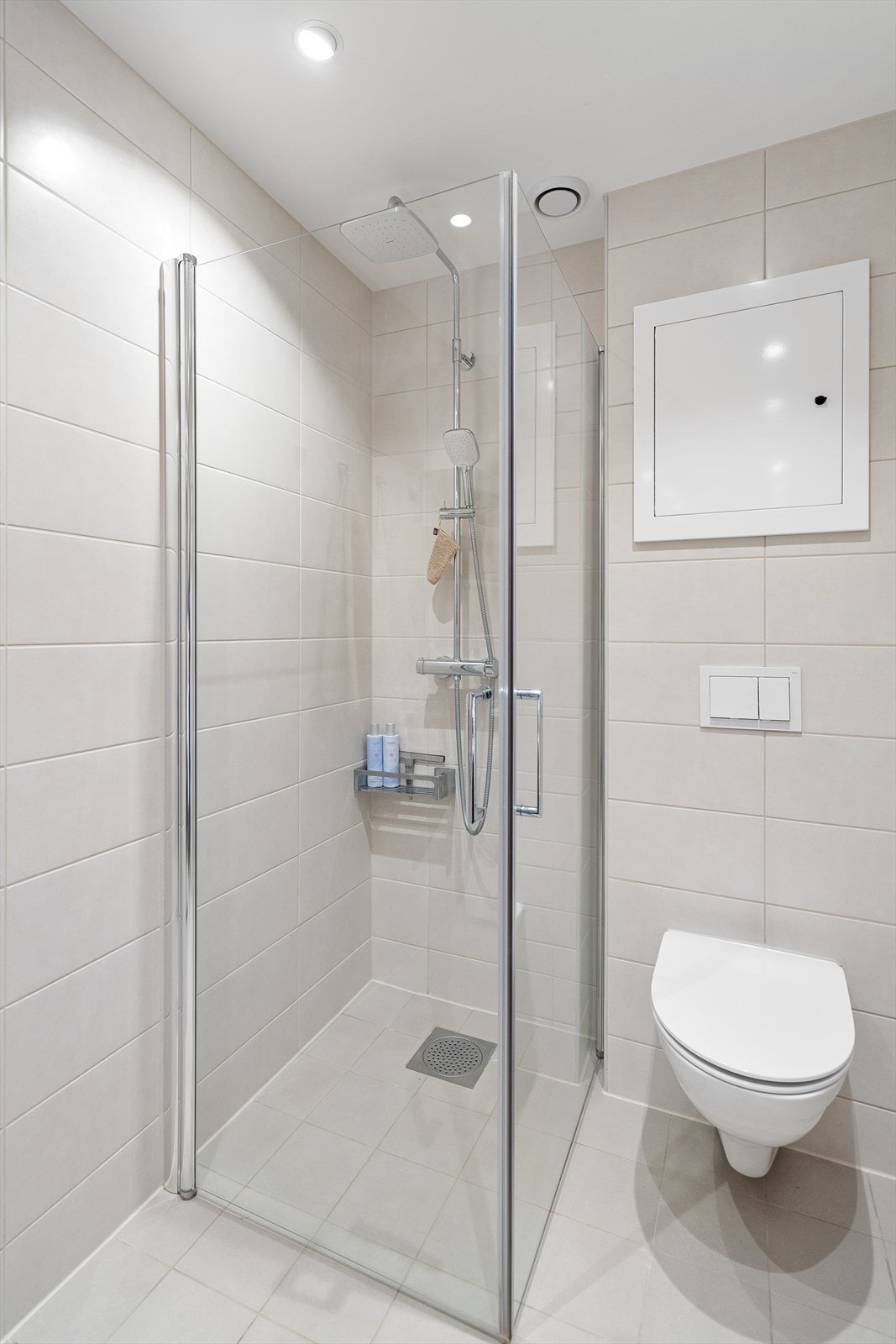 Rommet er innredet med vegghengt toalett, dusjhjørne med innfellbare glassdører og baderomsinnredning med skuffer, servant nedfelt i innredning og speil. Galleribilde