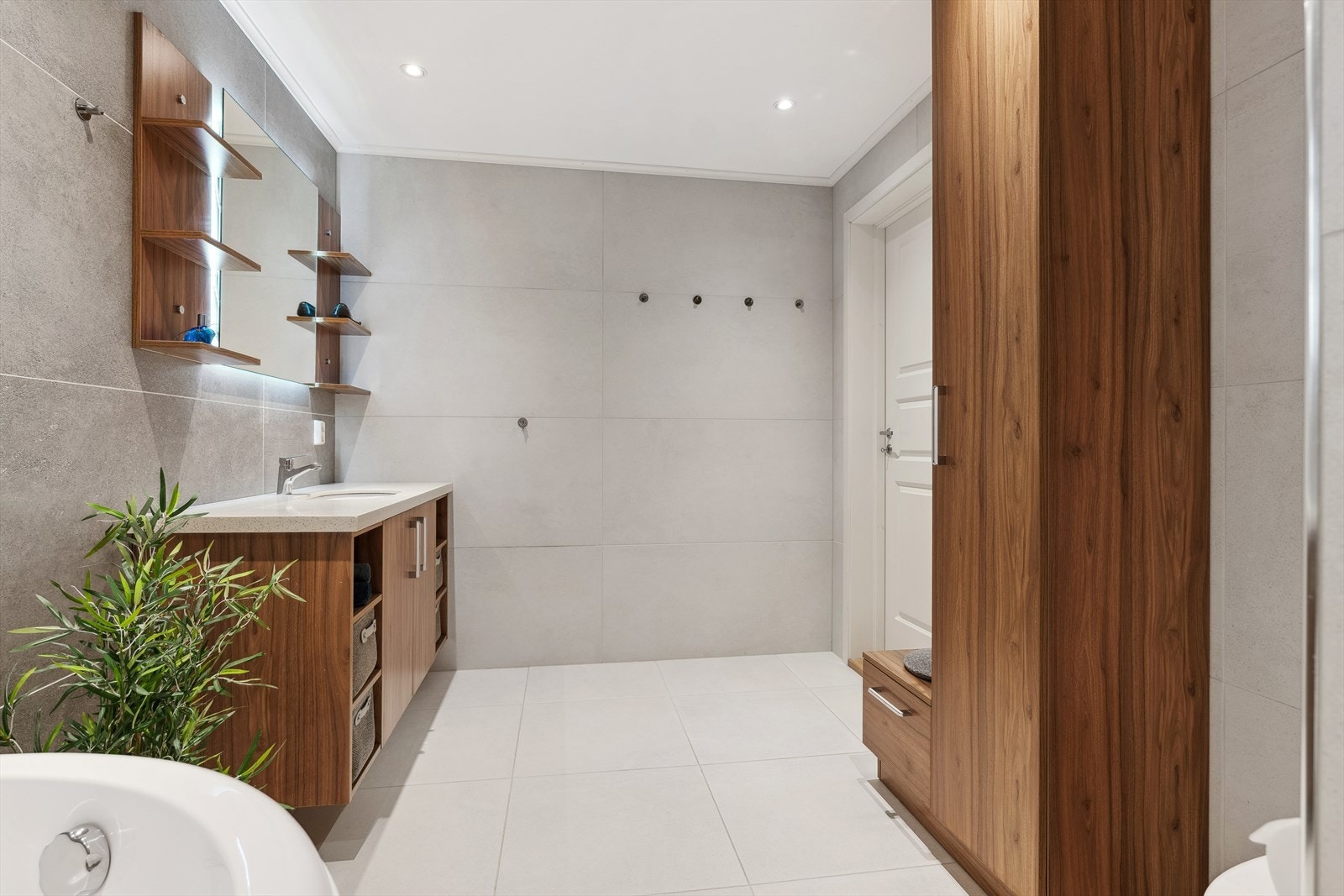 Badet er innredet med badekar til glede for store og små, badeormsinnrending med nedfelt servant og skapseksjon, høyskap montert på vegg, belyst speil, vegghengt toalett og dusjnisje med regnfallsdusj. Galleribilde