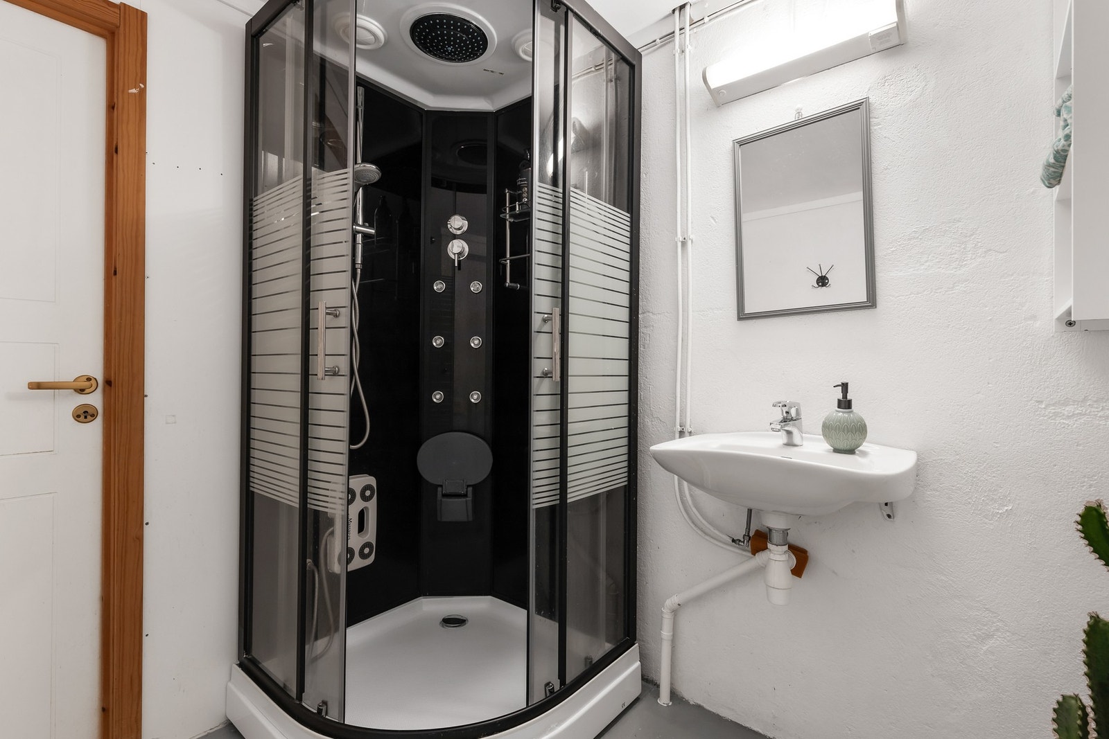 Badet er utstyrt med ddusjkabinett, gulvstående toalett og en vegghengt servant Galleribilde