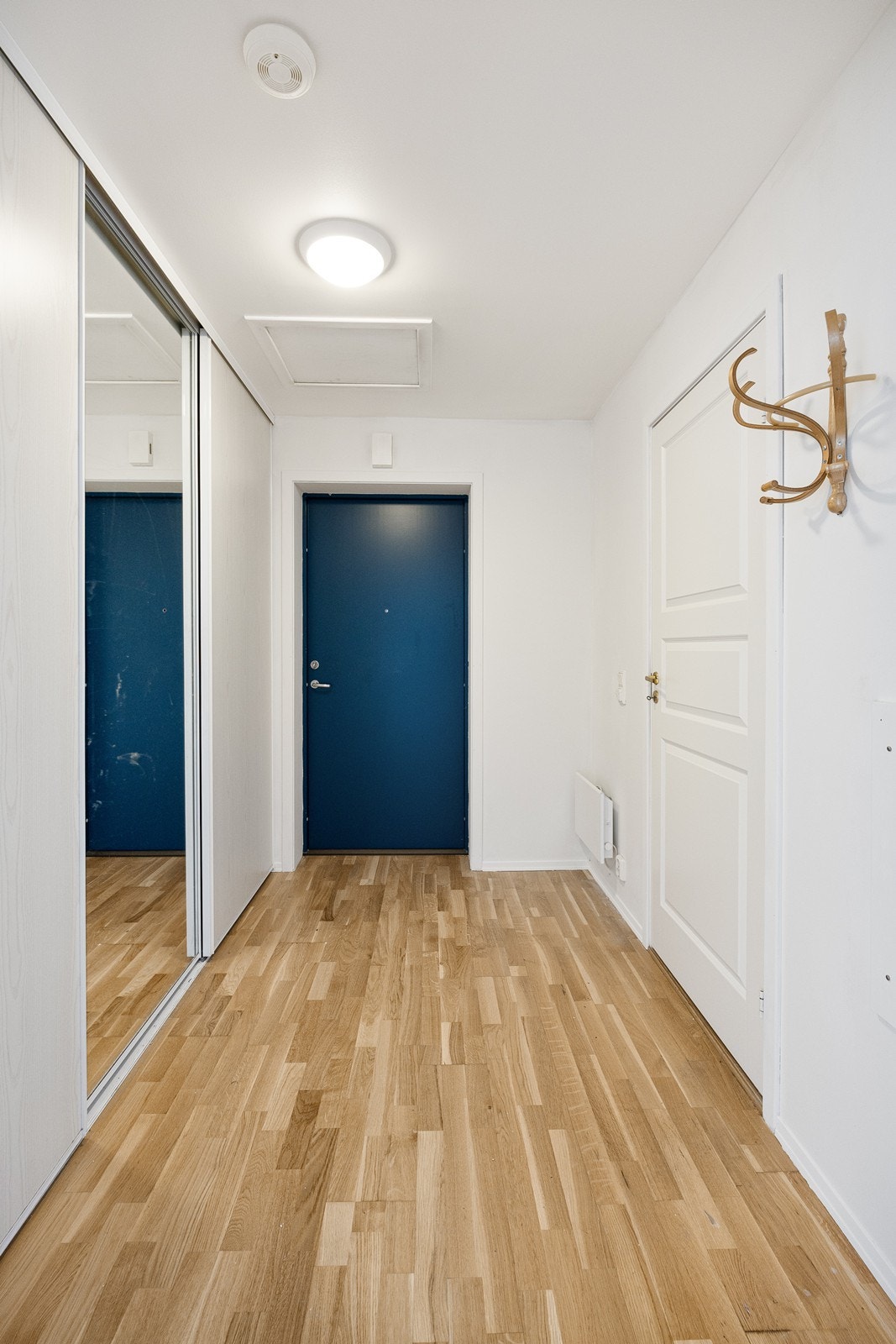 Entréen har lyse veggflater og parkett på gulvet. Galleribilde