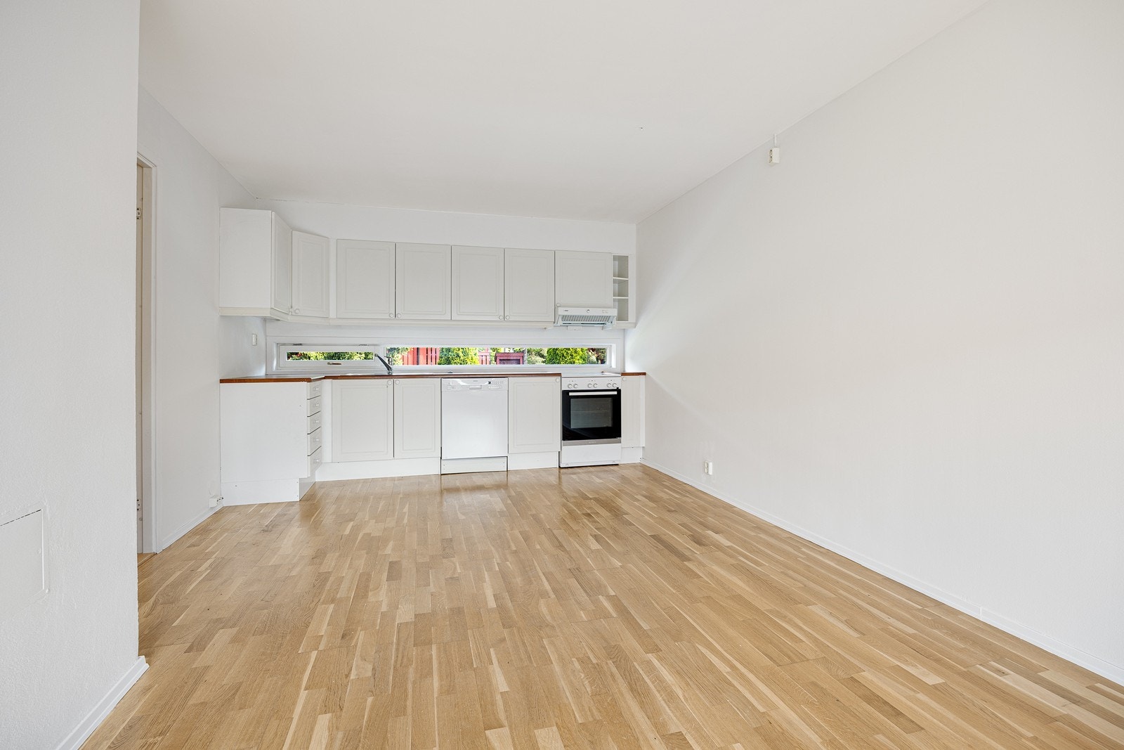 Kjøkkeninnredningen har hvite, profilerte fronter og laminatbenkeplate med nedfelt, dobbel oppvaskkum. Galleribilde