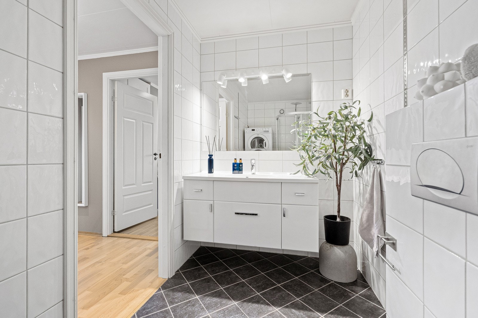 Pent bad- og kombinert vaskerom, pusset opp rundt 2014. Badet har flislagte overflater og varmekabler i gulv. Innredningen består av moderne servantmøblement med servant i helstøpt plate og tilhørende speil med toppmontert belysning. Galleribilde