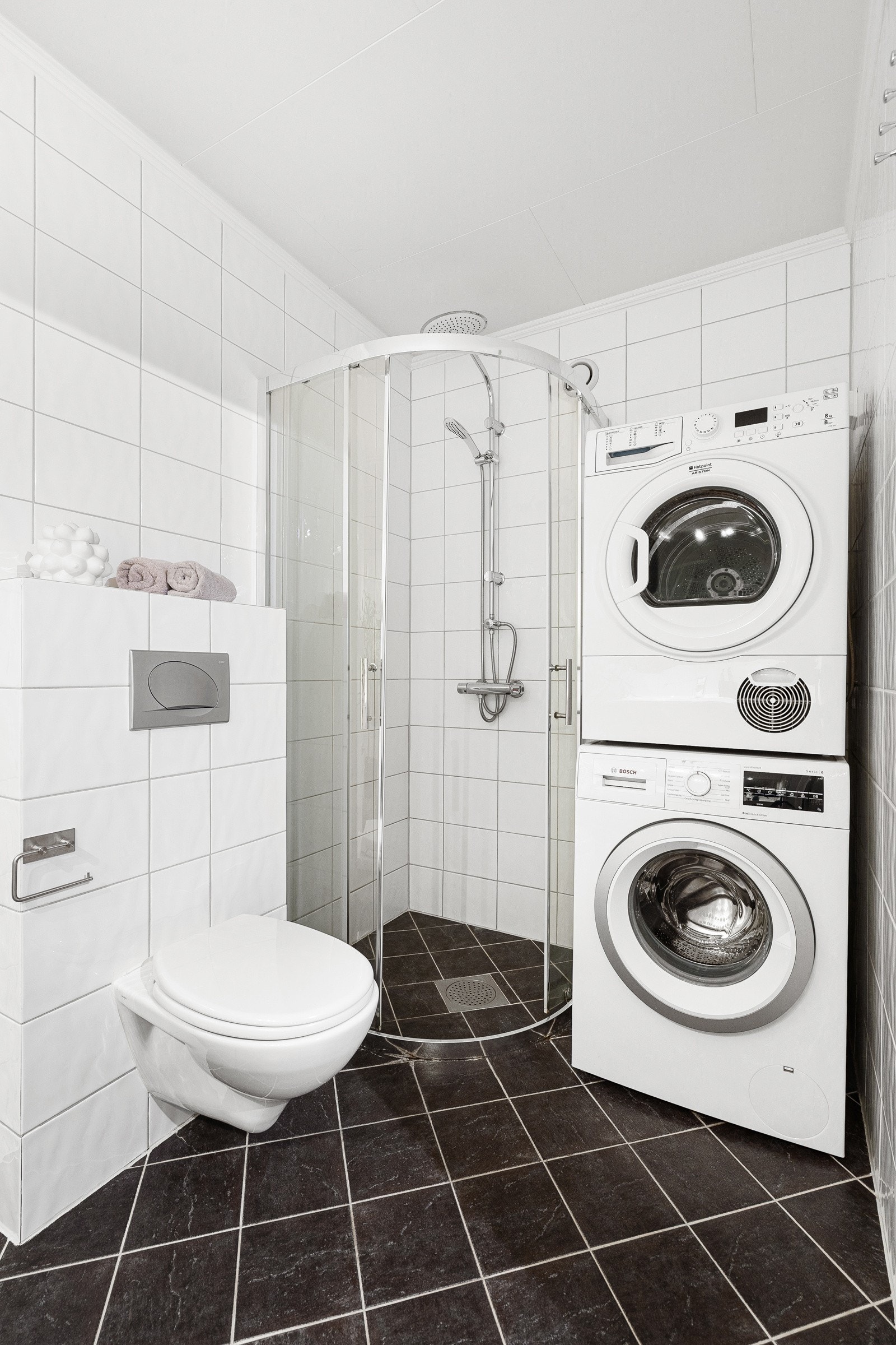 Videre har badet et vegghengt toalett, separat dusjhjørne med glassdører, samt opplegg og plass for både vaskemaskin og tørketrommel i vaskesøyle. Galleribilde