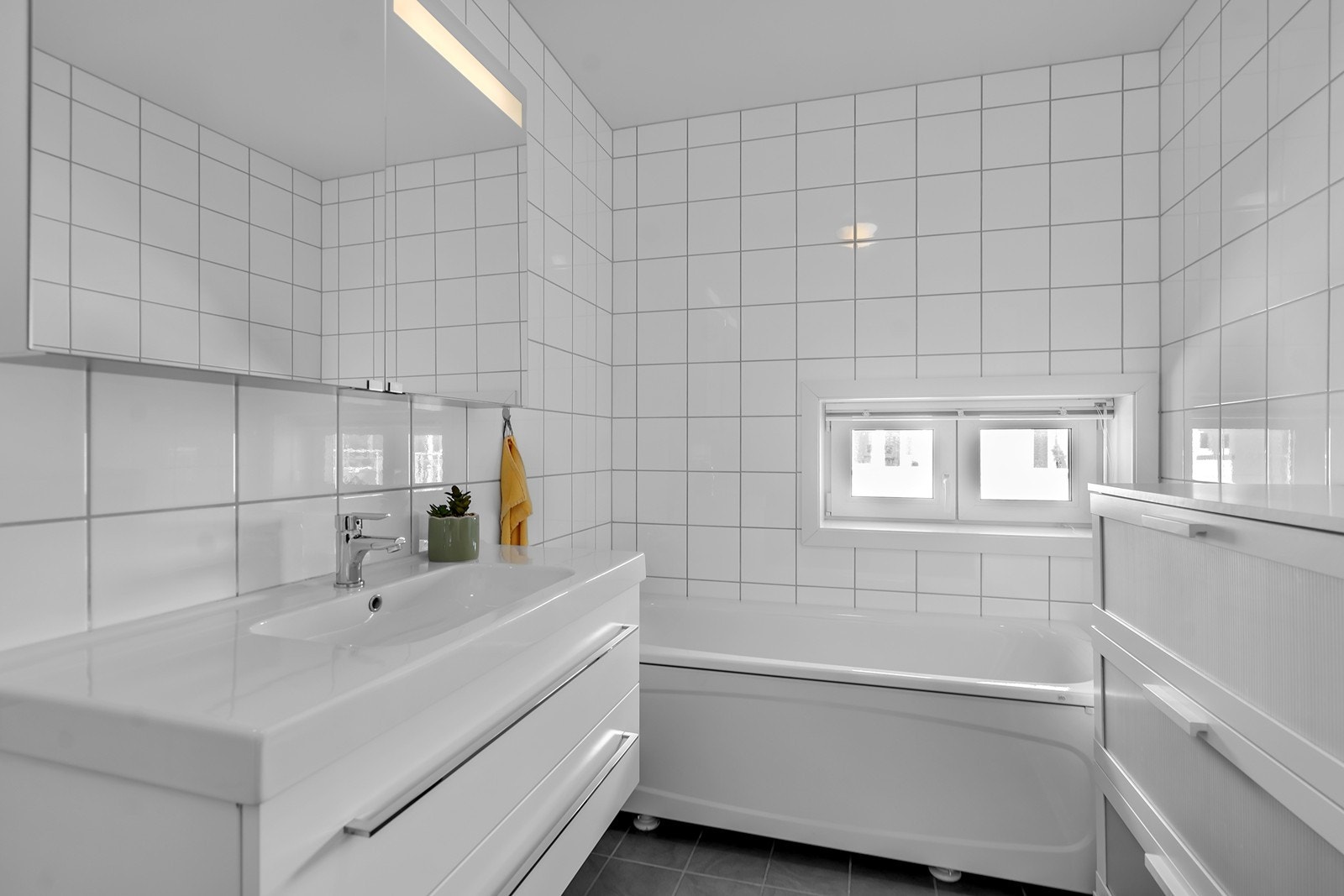 Badet er flislagt og utstyrt med toalett, baderomsinnredning og badekar. Galleribilde