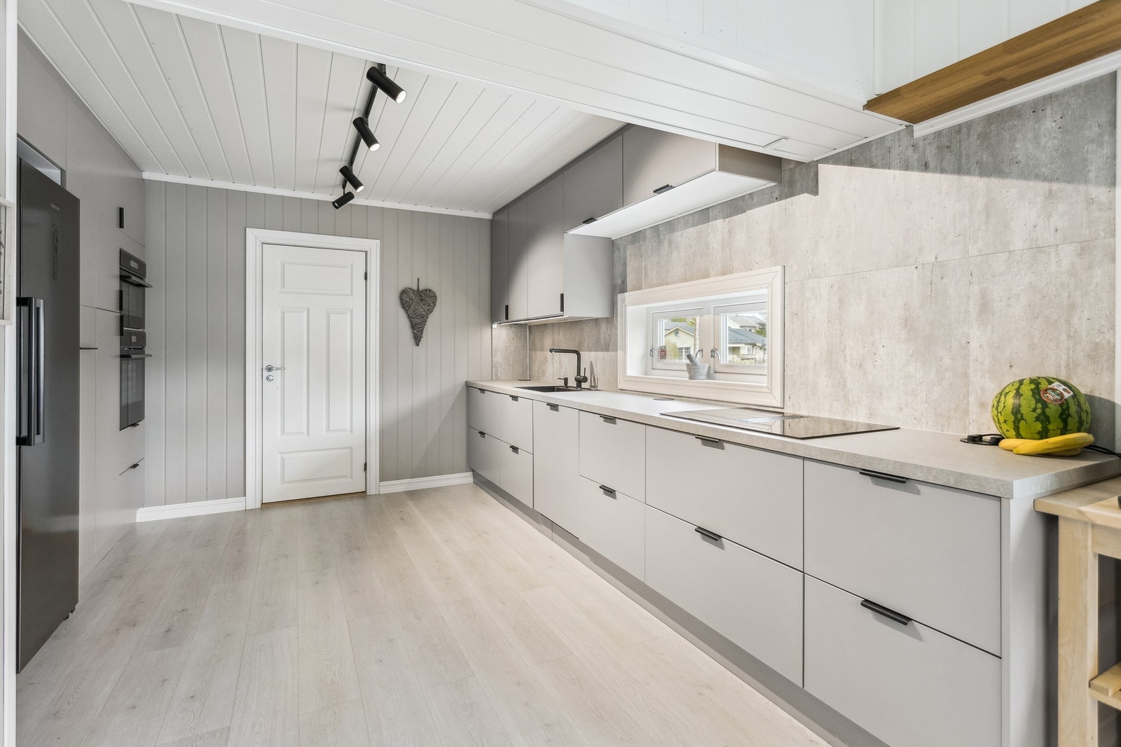 Kjøkkenet har integrerte hvitevarer som induksjonstopp, stekeovn, micro, oppvaskmaskin, vinskap og frittstående kjøl/fryseskap Galleribilde