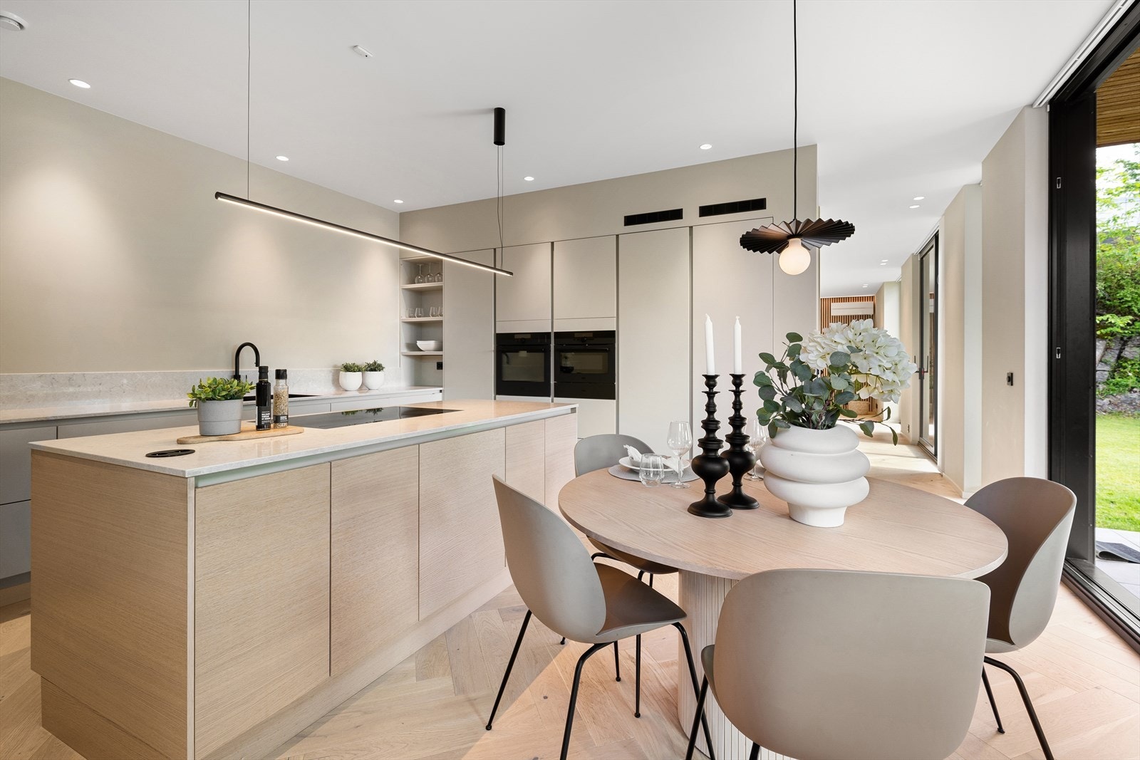 Den lekre kjøkkeninnredning fra HTH har beige glatte fronter med gripekant på skuffer og skap, samt benkeplater i lys stein. Galleribilde