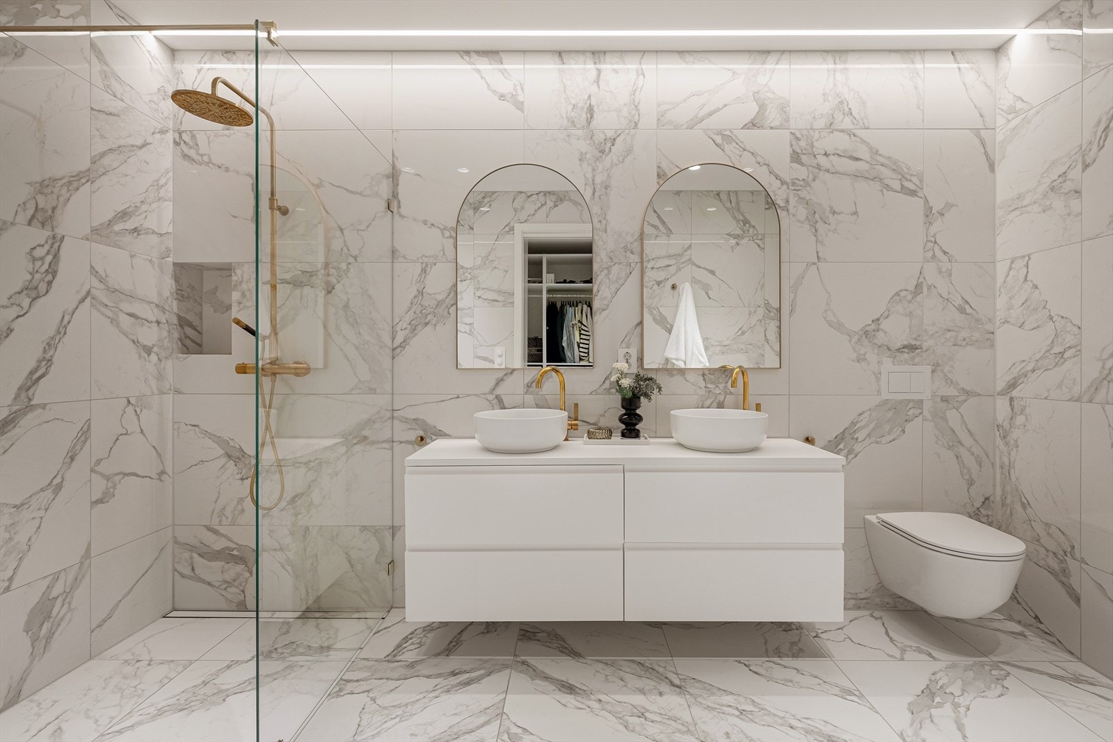 Rommet har innredning med 2 toppmonterte servanter, veggmontert toalett og dusjvegger/hjørne. Galleribilde