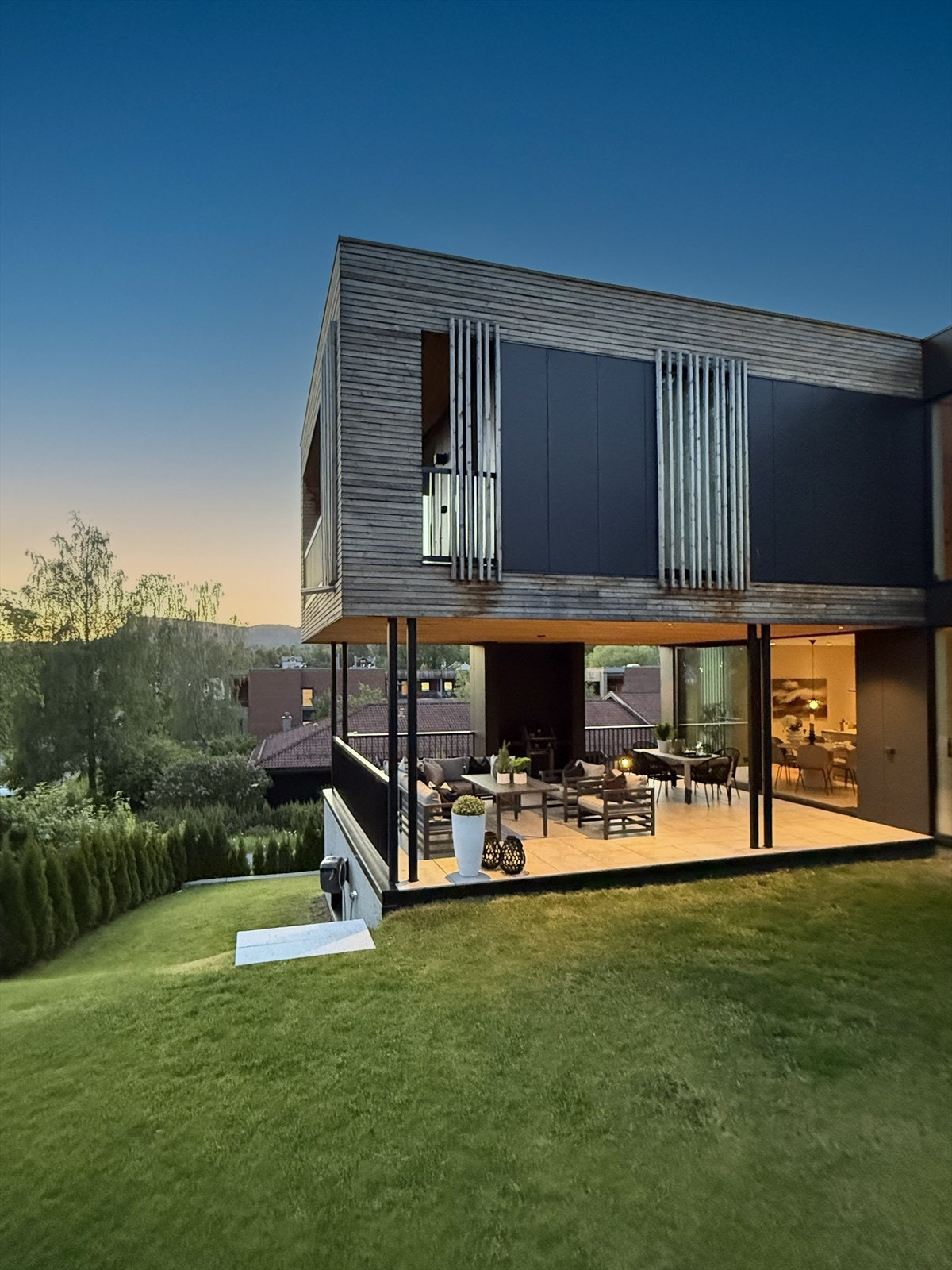 Fra kjøkkenet i 1. etasje er det direkte utgang til en stor og overbygget terrasse med videre adkomst til hagen. Dette gir en sømløs overgang mellom inne- og uteareal, og bidrar til å integrere terrassen i kjøkkenet, og motsatt. Galleribilde