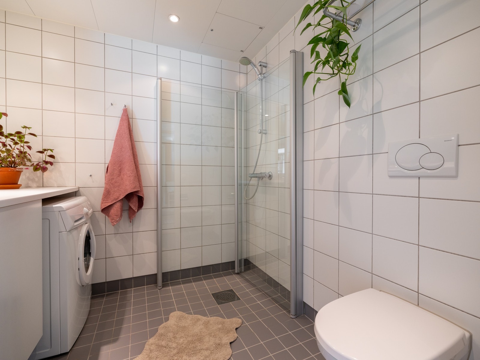 Innredningen består av servant på underskap, helstøpt speil, vegghengt toalett og dusjhjørne med svingbare dører. Galleribilde