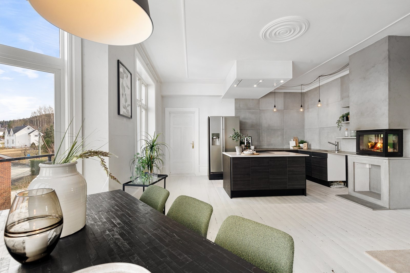 Videre inn kommer du til en åpen stue og kjøkkenløsning - det er eldre, malt tregulv samt rosett i taket - den gode takhøyden gir en meget god romfølelse Galleribilde