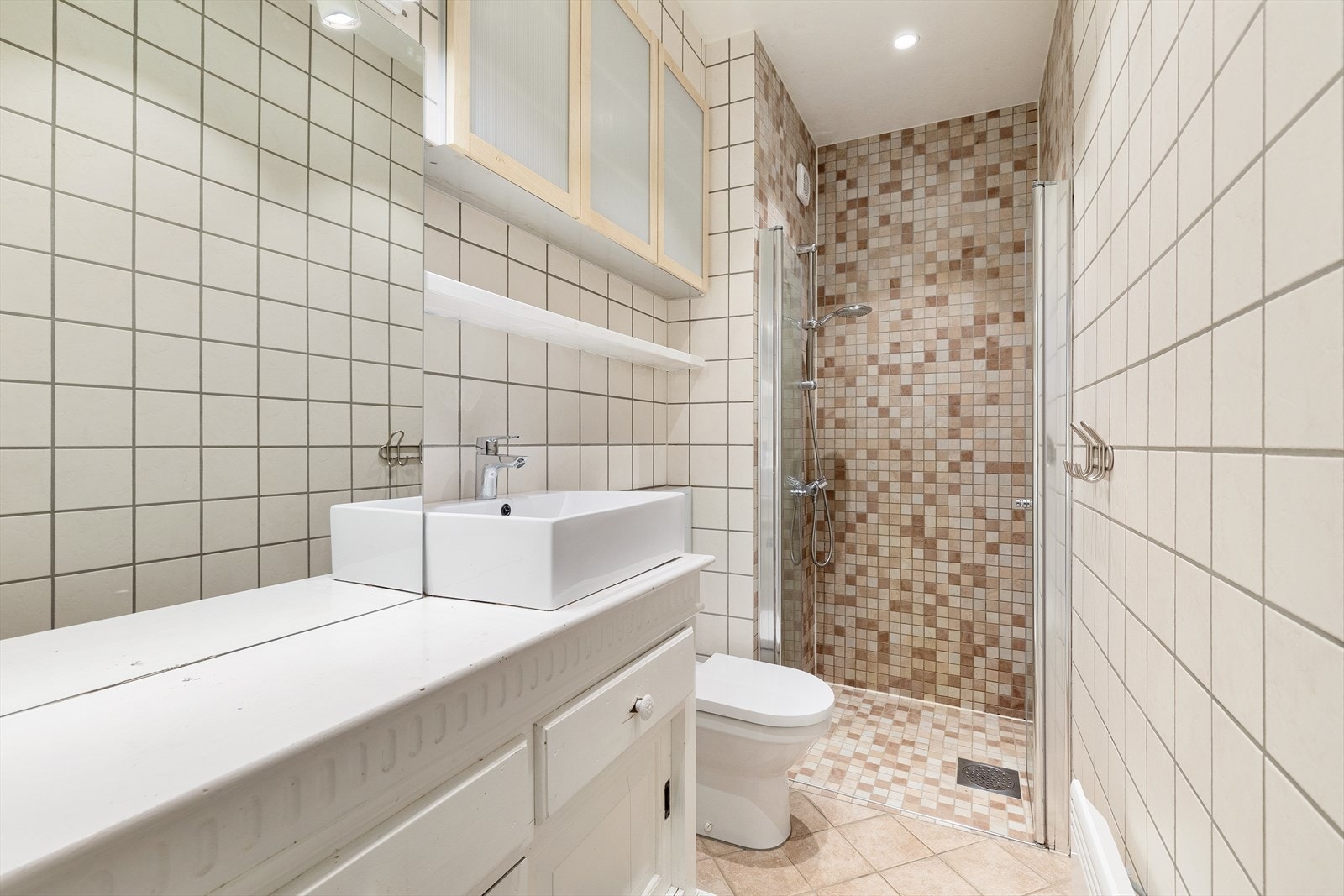 Lyst og pent flislagt bad med dusjhjørne, toalett, servant i innredning og diverse møblement - Se tilstandsrapport for kommentarer om badet Galleribilde