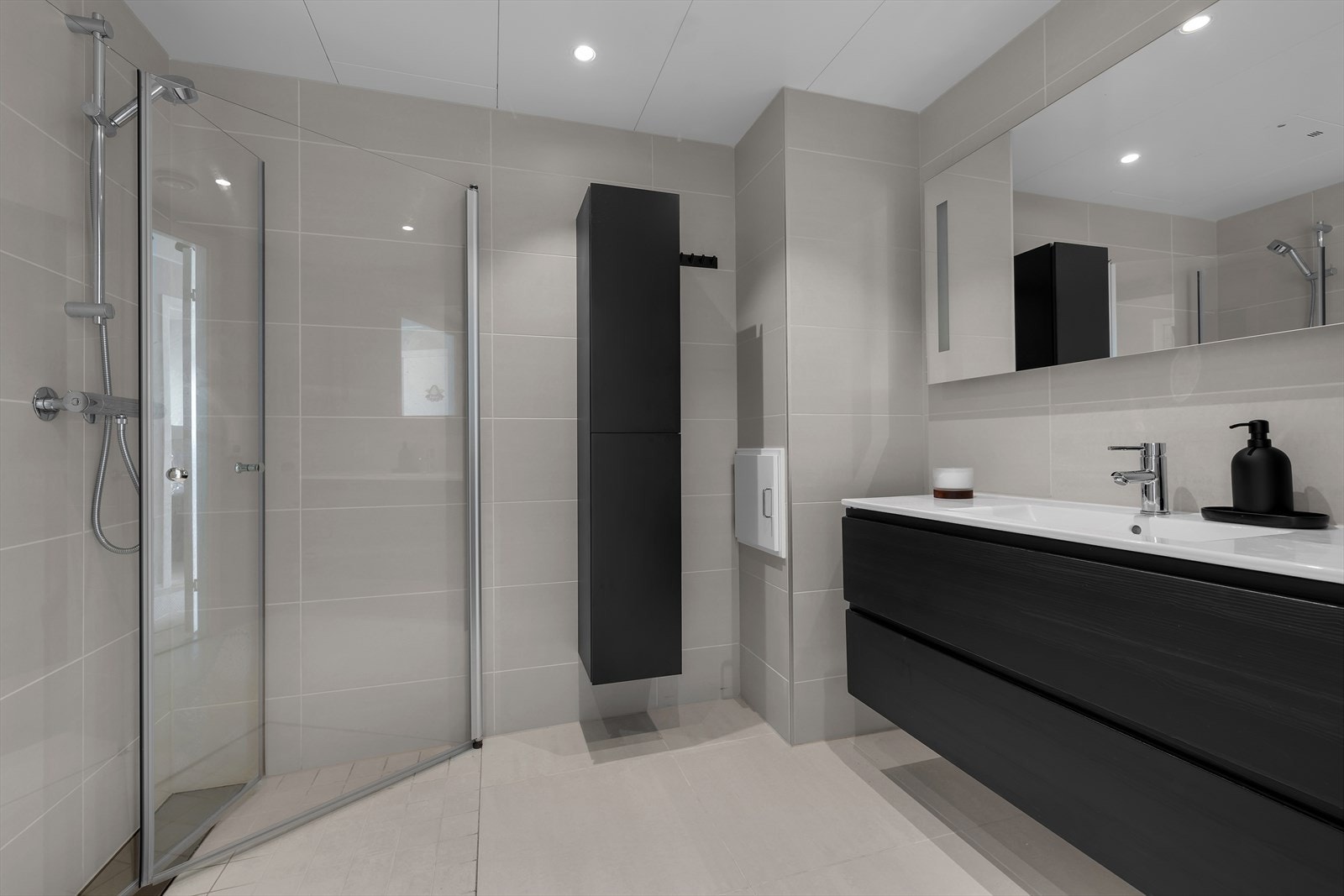 Moderne baderom med rene linjer og god oppbevaringsplass. Flislagt gulv og vegger, samt en romslig dusjløsning med innslagbare dusjdører. Galleribilde