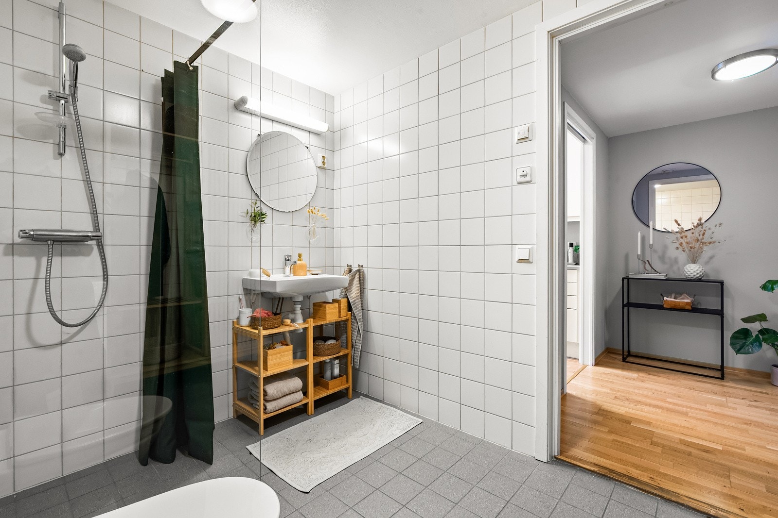 Baderommet inneholder servant, speil med overbelysning, gulvstående høyskap, toalett og dusjhjørne (2022). Galleribilde